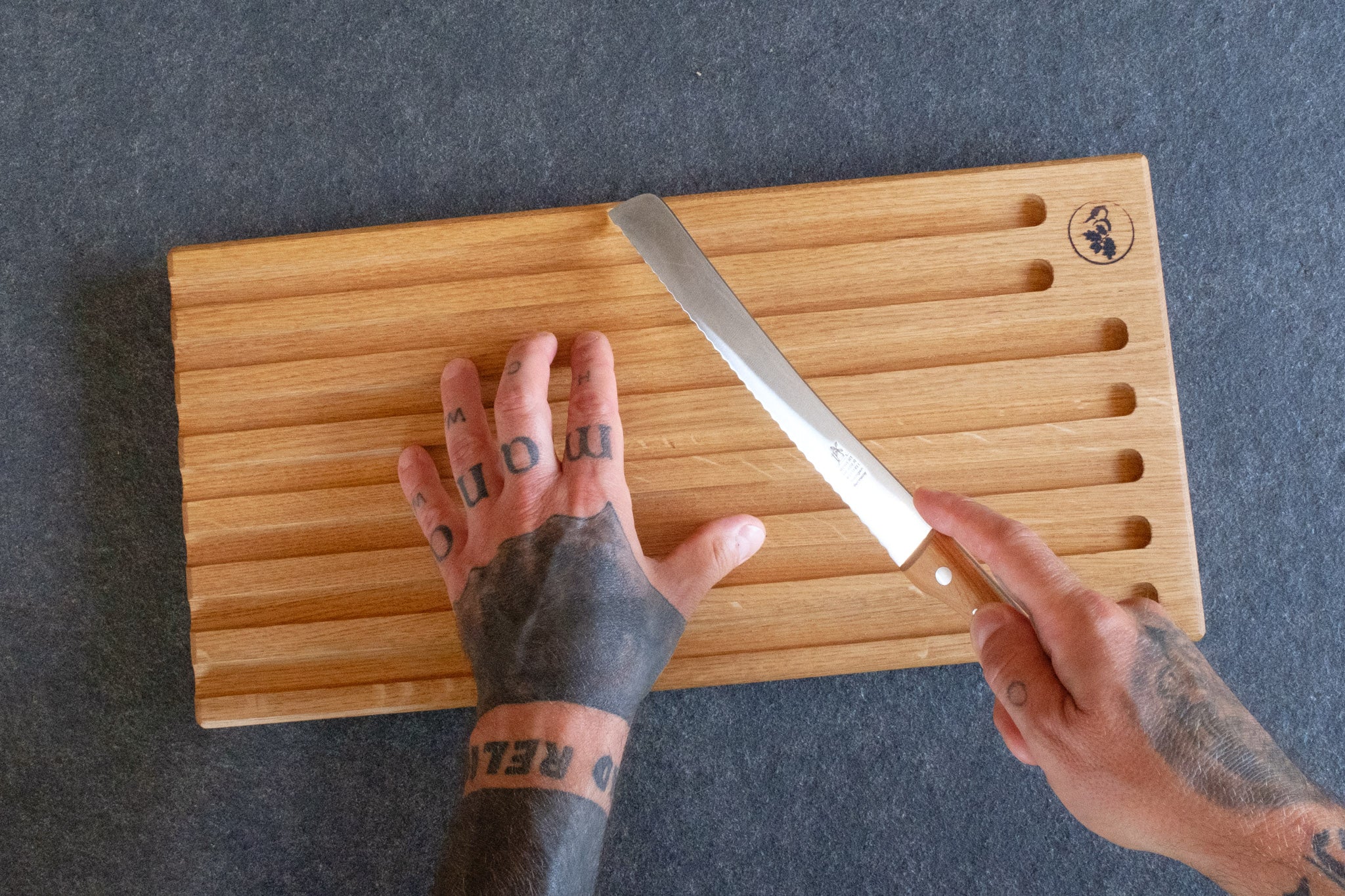 gehaltenes Brotsägemesser auf Brotbrett aus Eiche
