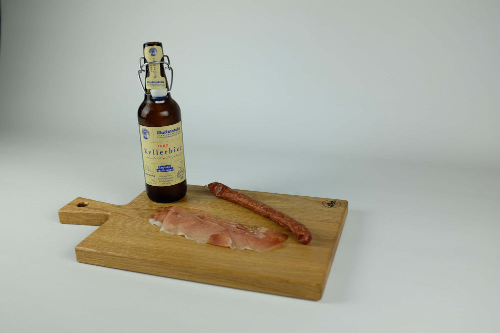 Brotzeitbrett mit Schinken, Wurst und Bierflasche