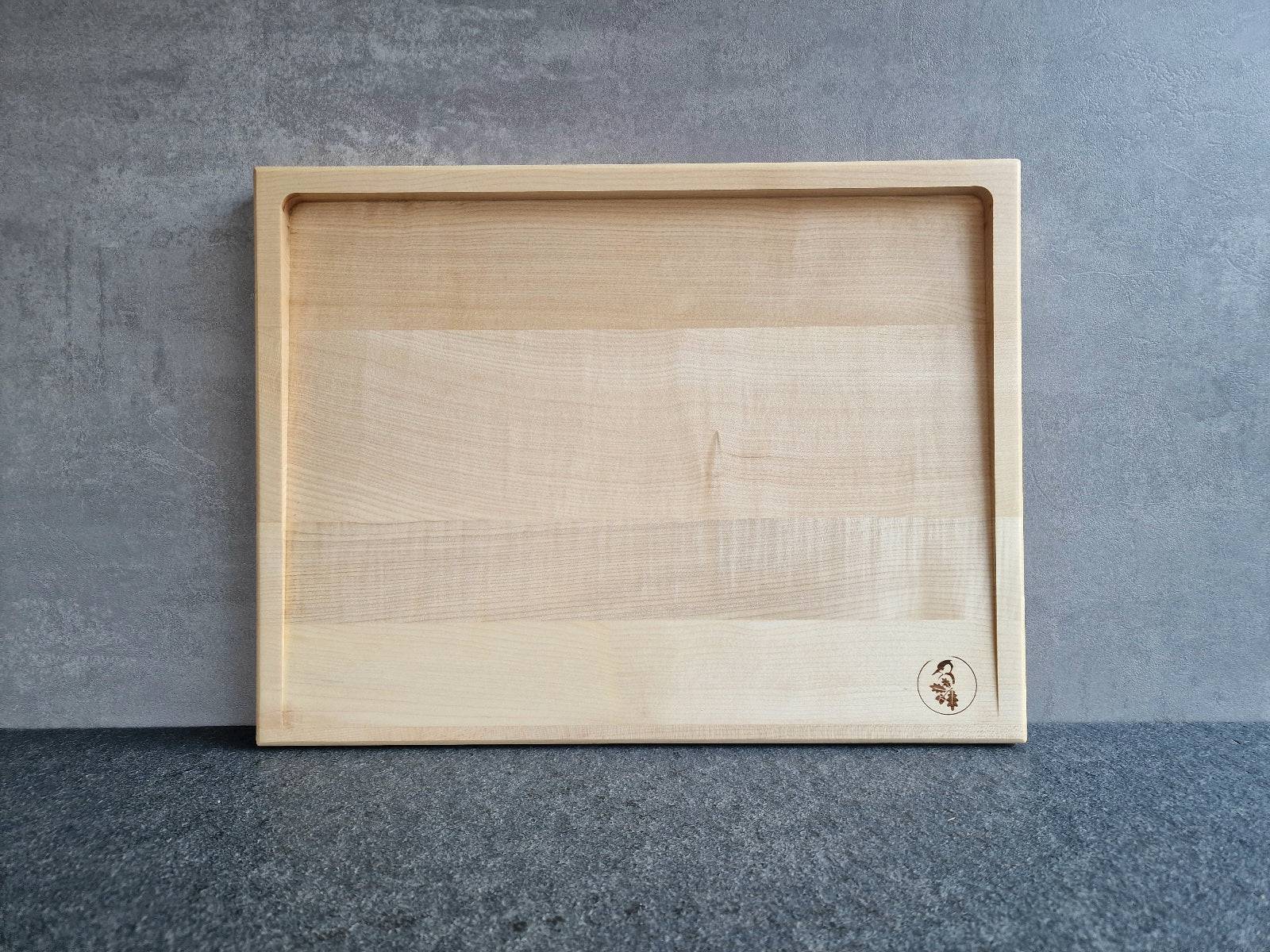 Helles Tranchierbrett aus Ahorn an einer Betonwand