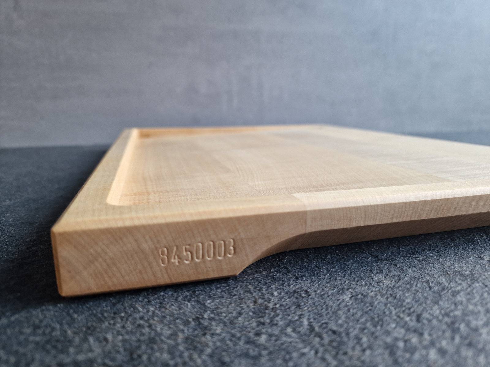 Von Hand eingeschlagene Seriennummer an einem Tranchierbrett aus massivem Ahorn.