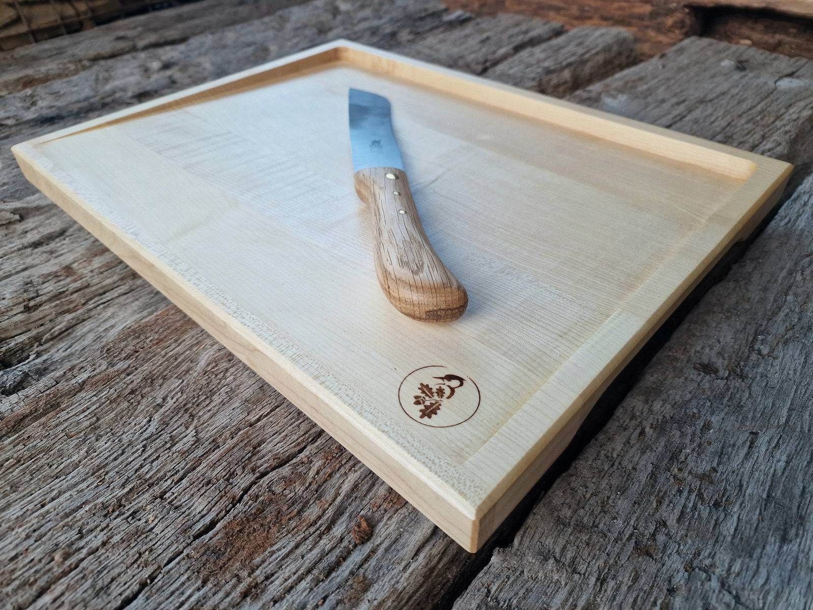 Ahorn Tranchierbrett mit einem Brotmesser auf alten Eichenbalken.