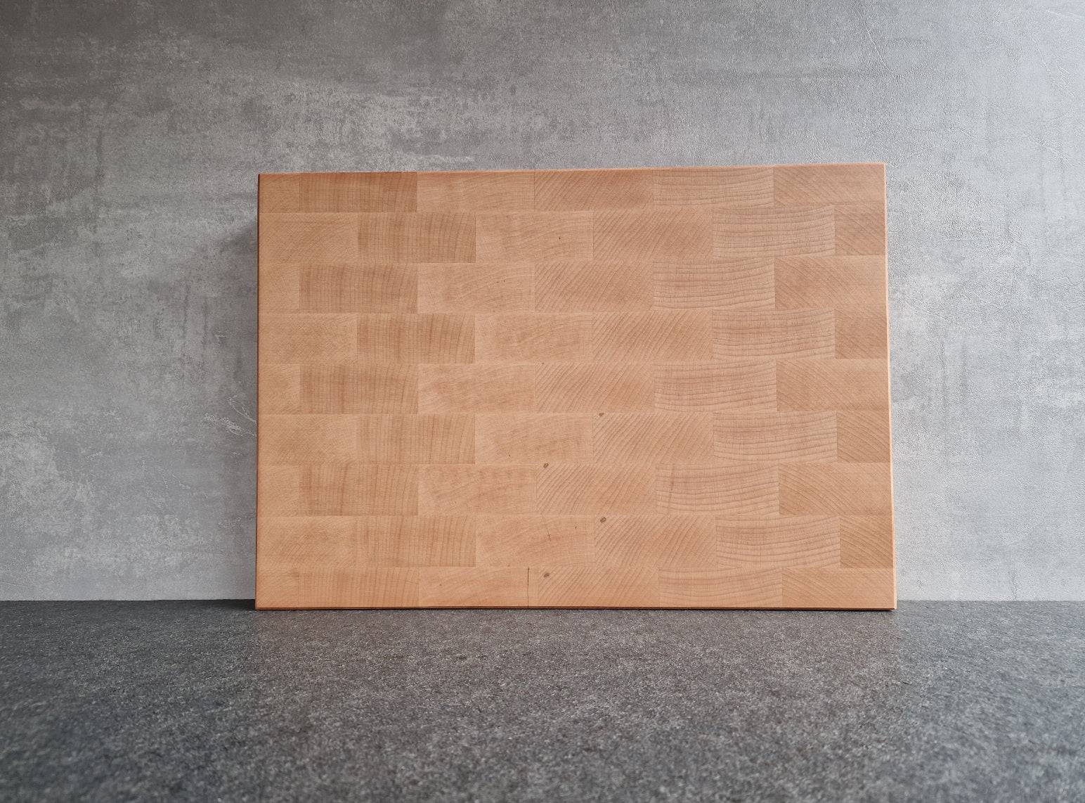 RückseiteStirnholz Schneidebrett aus Buche stehend vor einer Betonwand