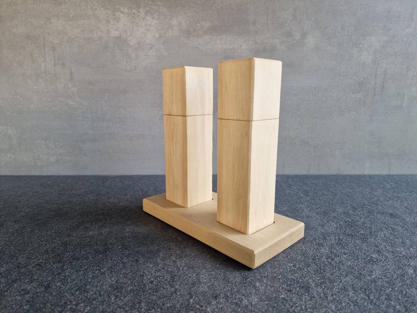 Seitenansicht einer Salzmühle und Pfeffermühle auf einem Mühlenteller mit Mulden aus massiver Hainbuche.