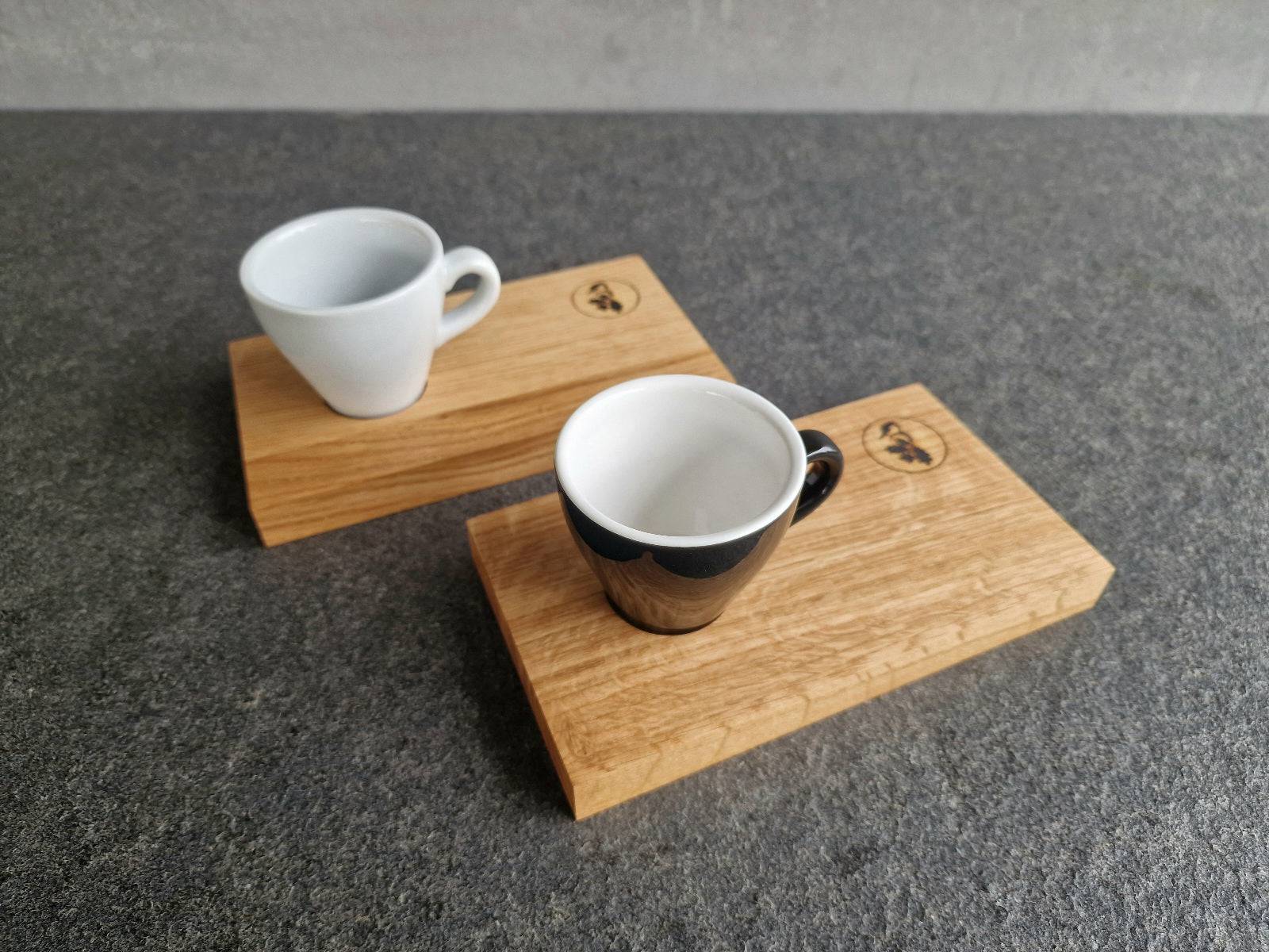 2 Eiche Espressotabletts mit Mulde. Eines mit einer weißen und eines mit einer schwarzen Espressotasse.
