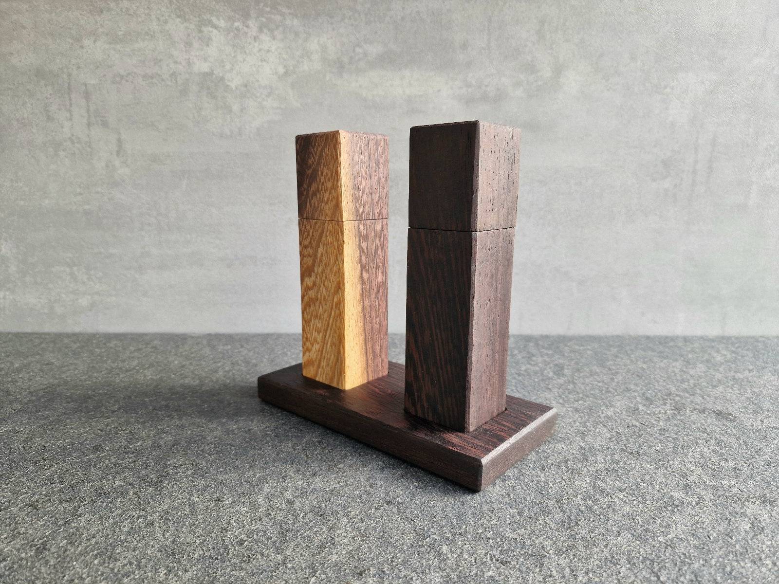 Wenge mit gelbem Splint Mühle und schwarz-braune Wenge Mühlen auf einem Holz Teller.