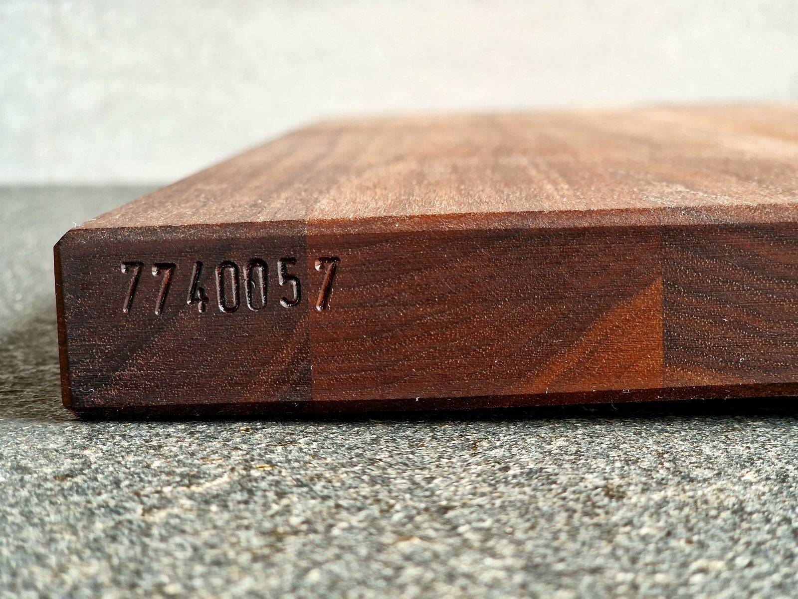 Eingeschlagene Seriennummer seitlich in einer Kochfeldabdeckung von Spessartbrett.