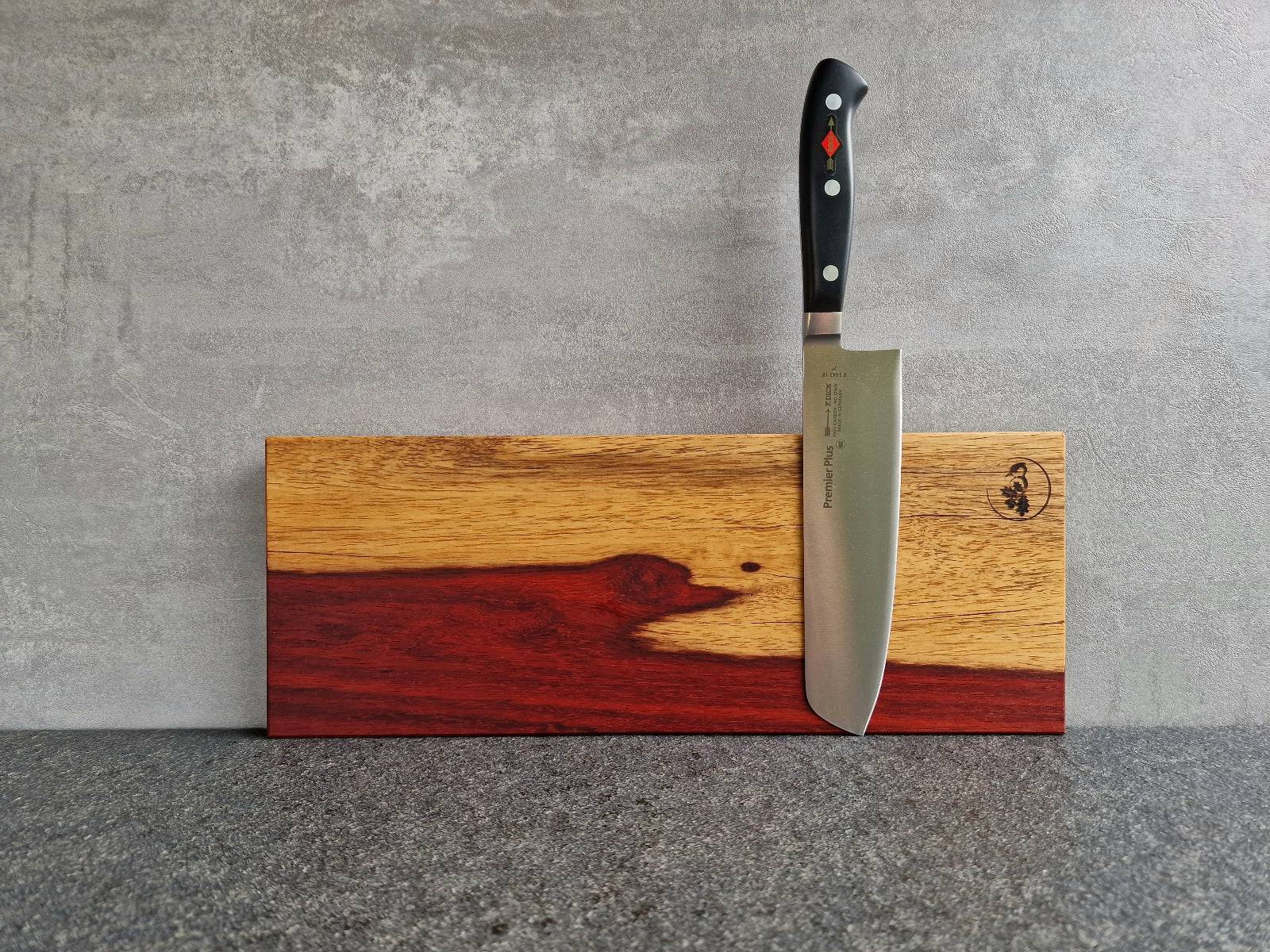 Magnetische Messerleiste aus rotem Padouk mit hellem Splint durchzogen. Montiert an einer Betonwand mit einem Dick Usuba Gemüsemesser.