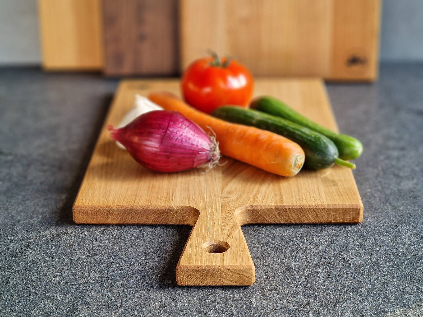 Zwiebel, Karotte, Gurke und Tomate auf einem Eiche Stielbrett.