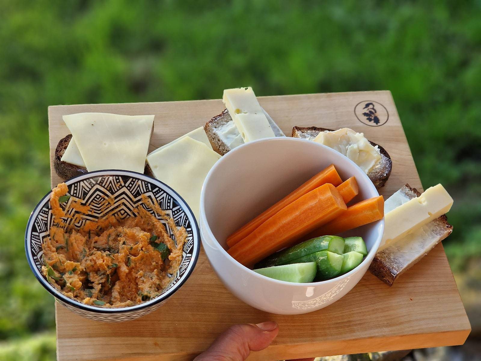 Deftige Brotzeit mit Karotten und Gurken auf einem Holzbrett aus Vogelbeere.