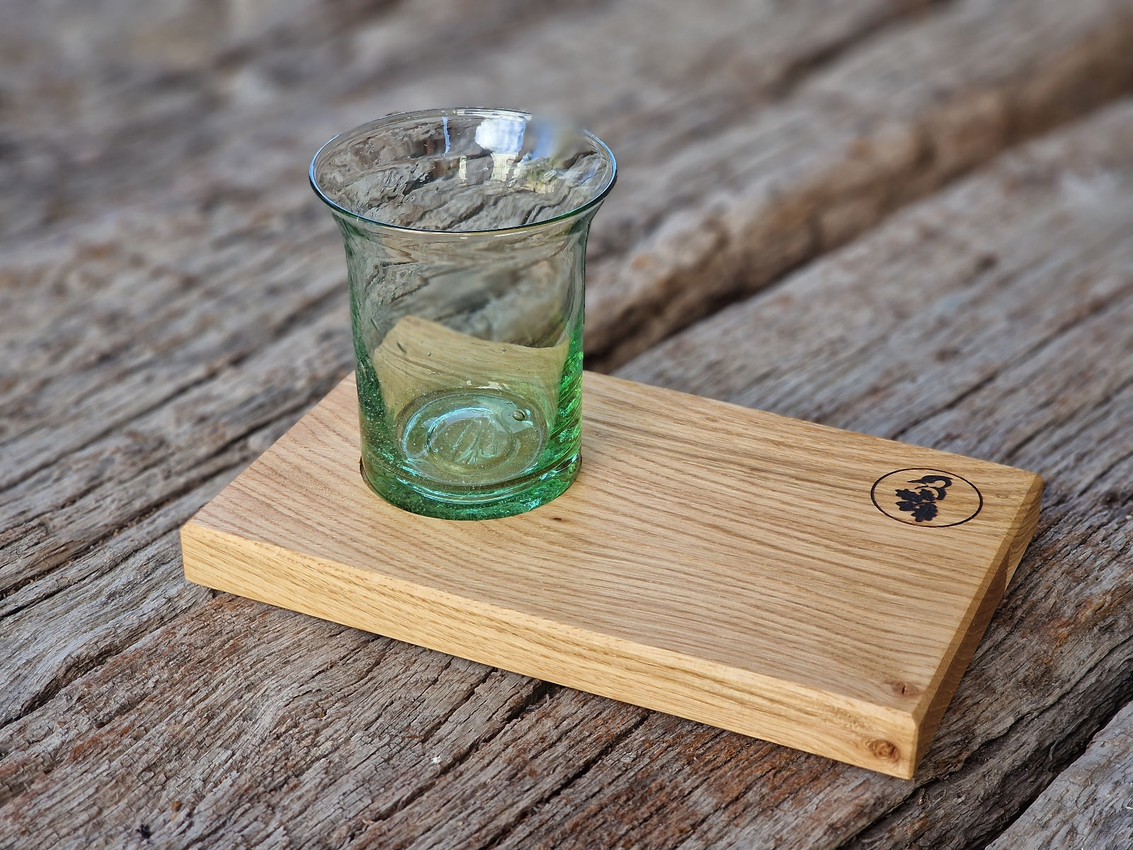 Grünes Wasserglas aus Thüringen, mundgeblasen mit Gispen, auf einem Holz Tablett aus Eiche.