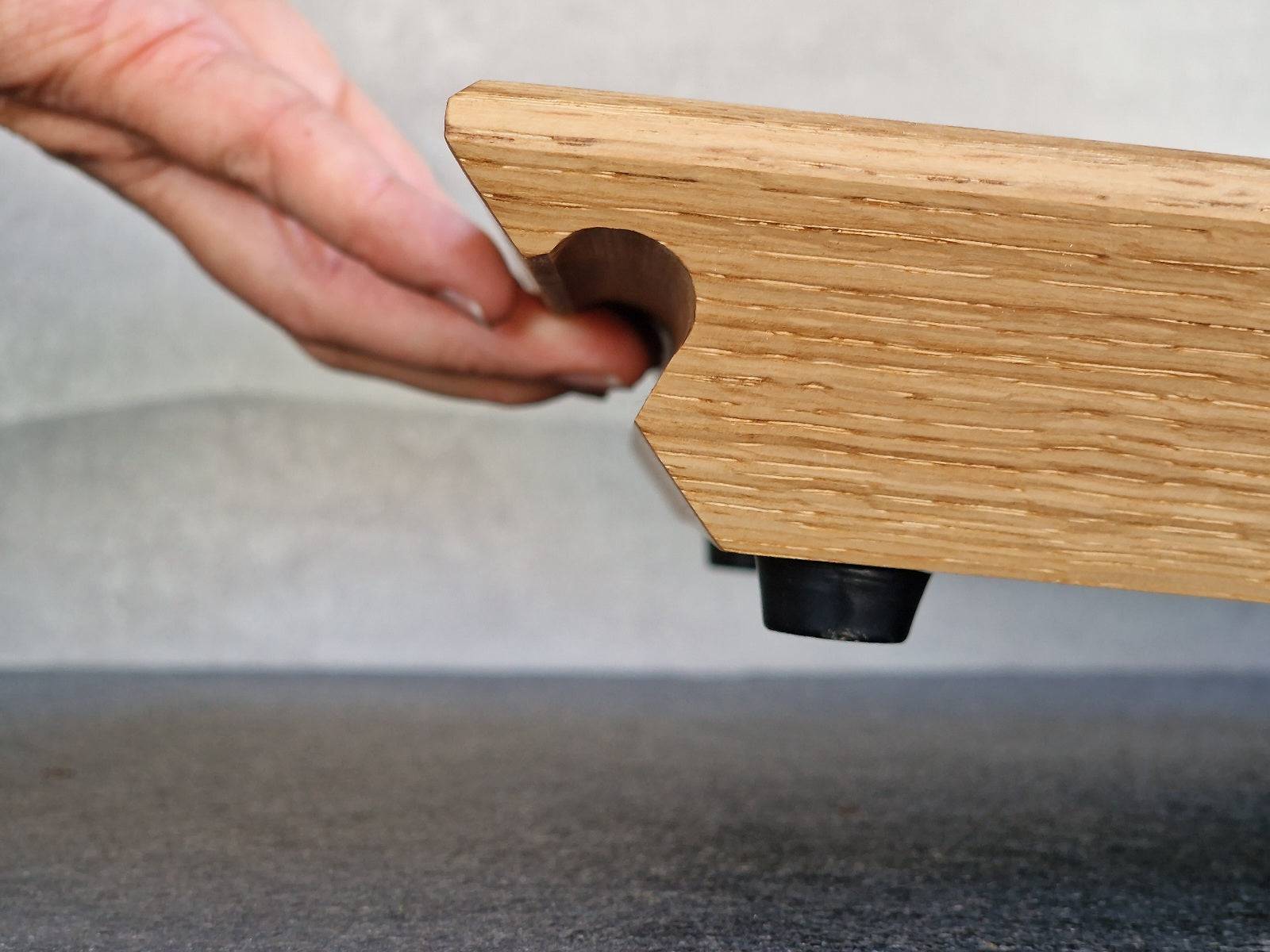 Eine Hand hebt in der Griffmulde ein Gleitbrett an.