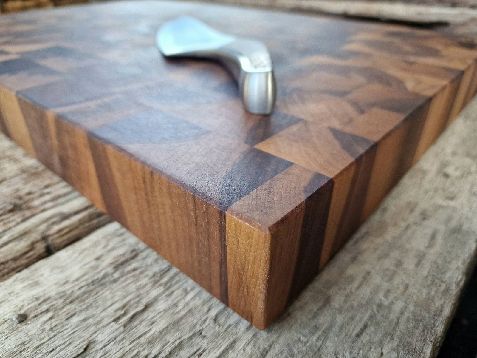 Eckansicht eines Nussbaum Hirnholz Schneideblockes mit einem GĂŒde Kochmesser.