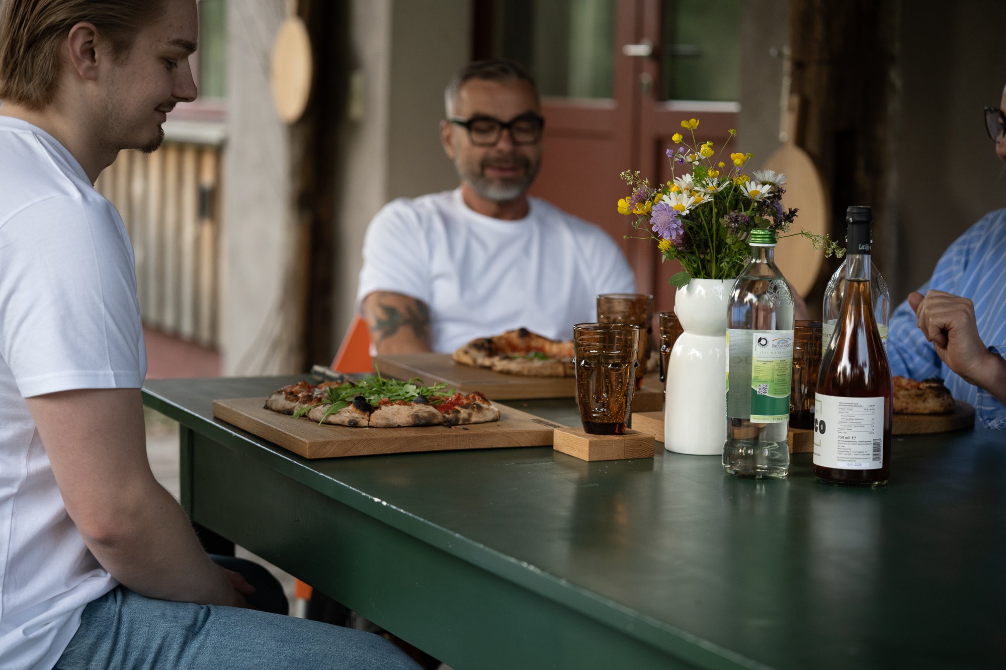 Gemeinschaftliches Pizza essen auf der Terrasse mit schönen Holzbrettern.