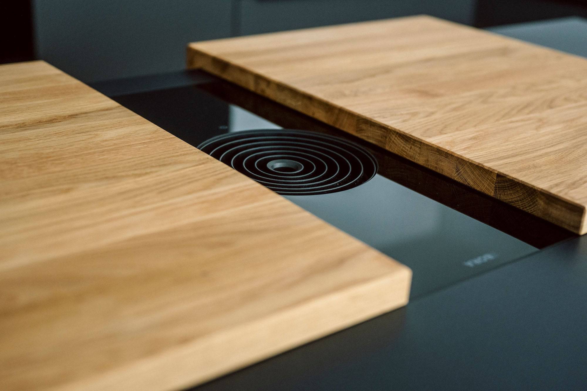 Detailaufnahme eines Bora Kochfeldes auf dem eine zweiteilige Abdeckung aus Eiche liegt