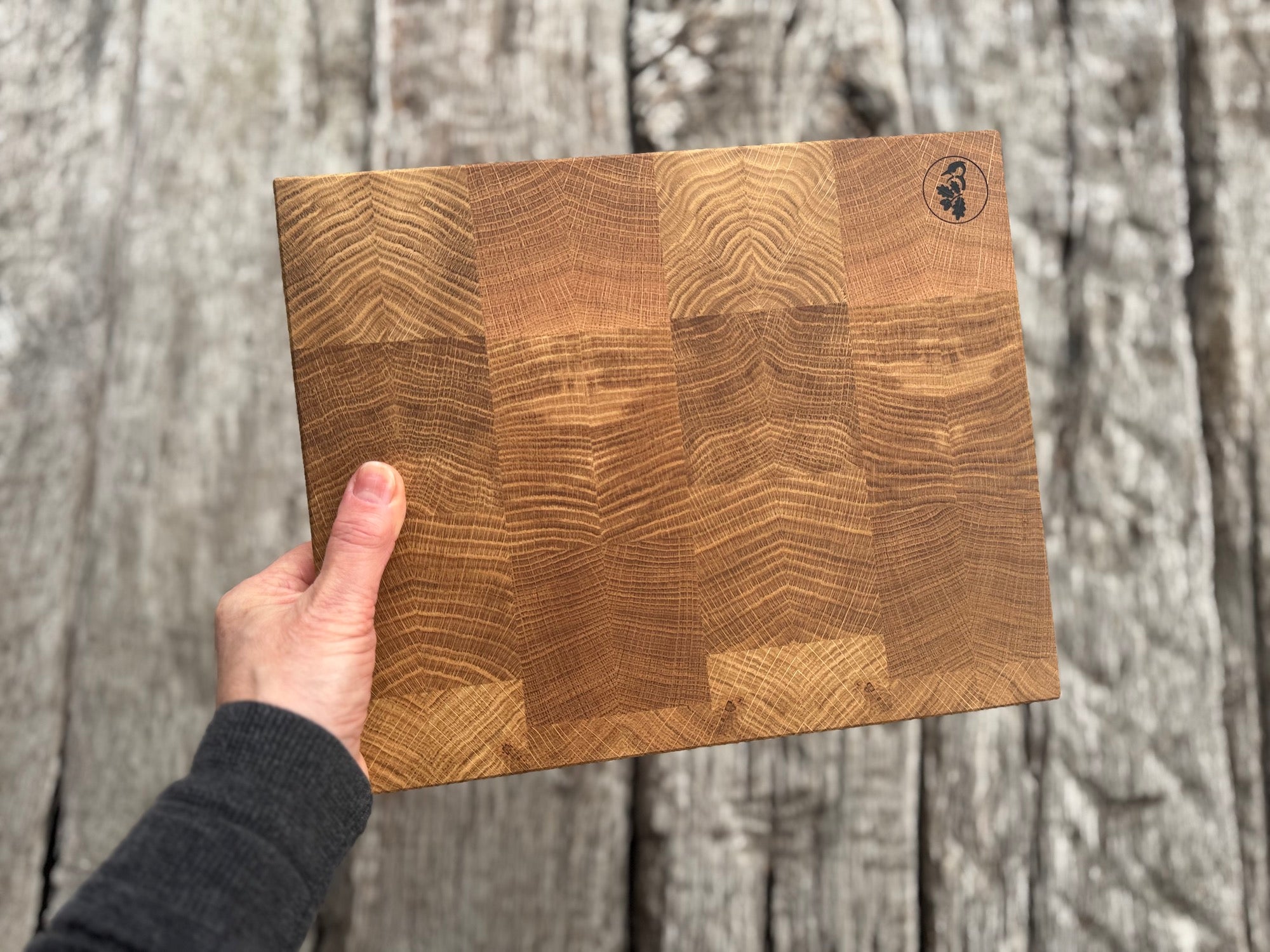 Hand hält 30 cm breites Stirnholz Schneidebrett in die Höhe.