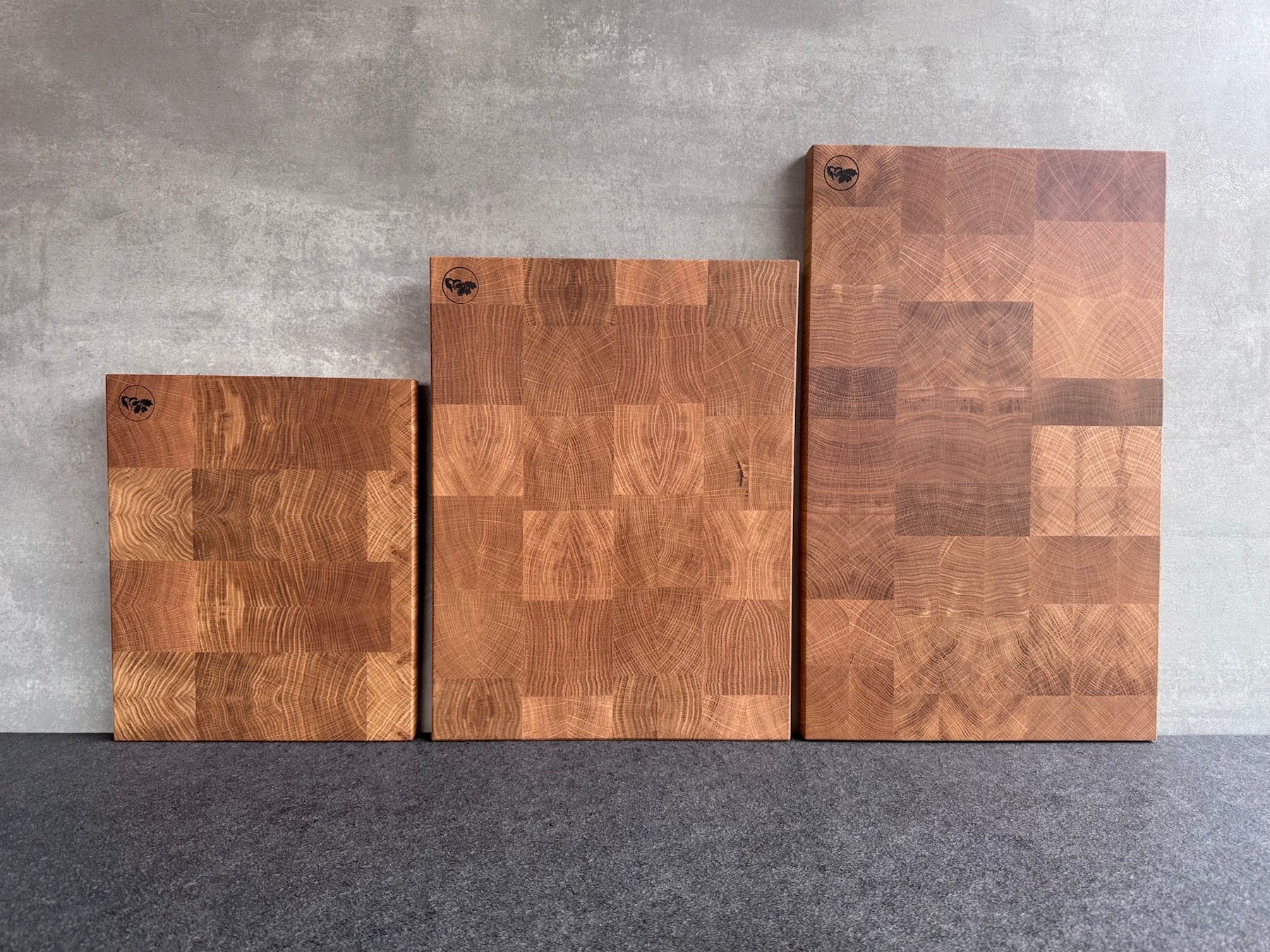 3 verschieden große Eiche Hirnholz Schneidebretter an einer Betonwand aufgestellt.