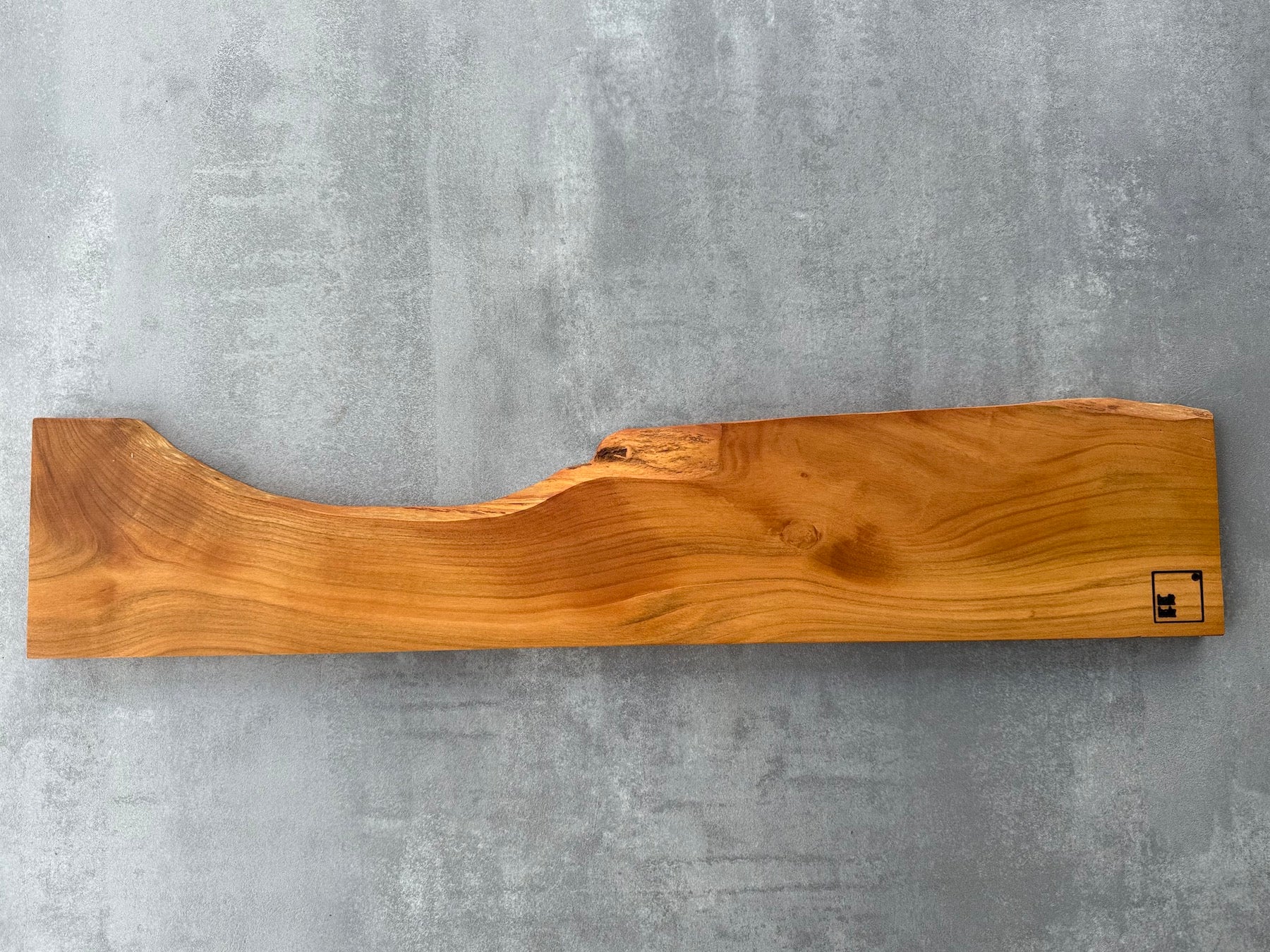 Magnetische Messerleiste aus Kirschbaumholz aus einem Stück an einer Betonwand.