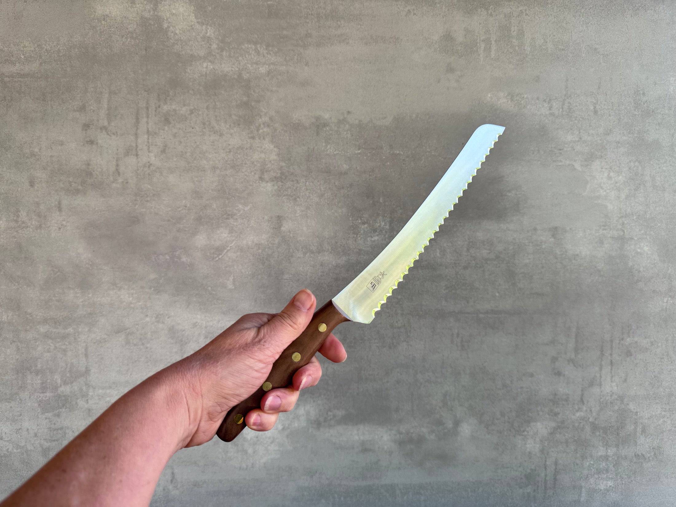 Hand hält ein Brotmesser Brotbeidhänder in die Luft.