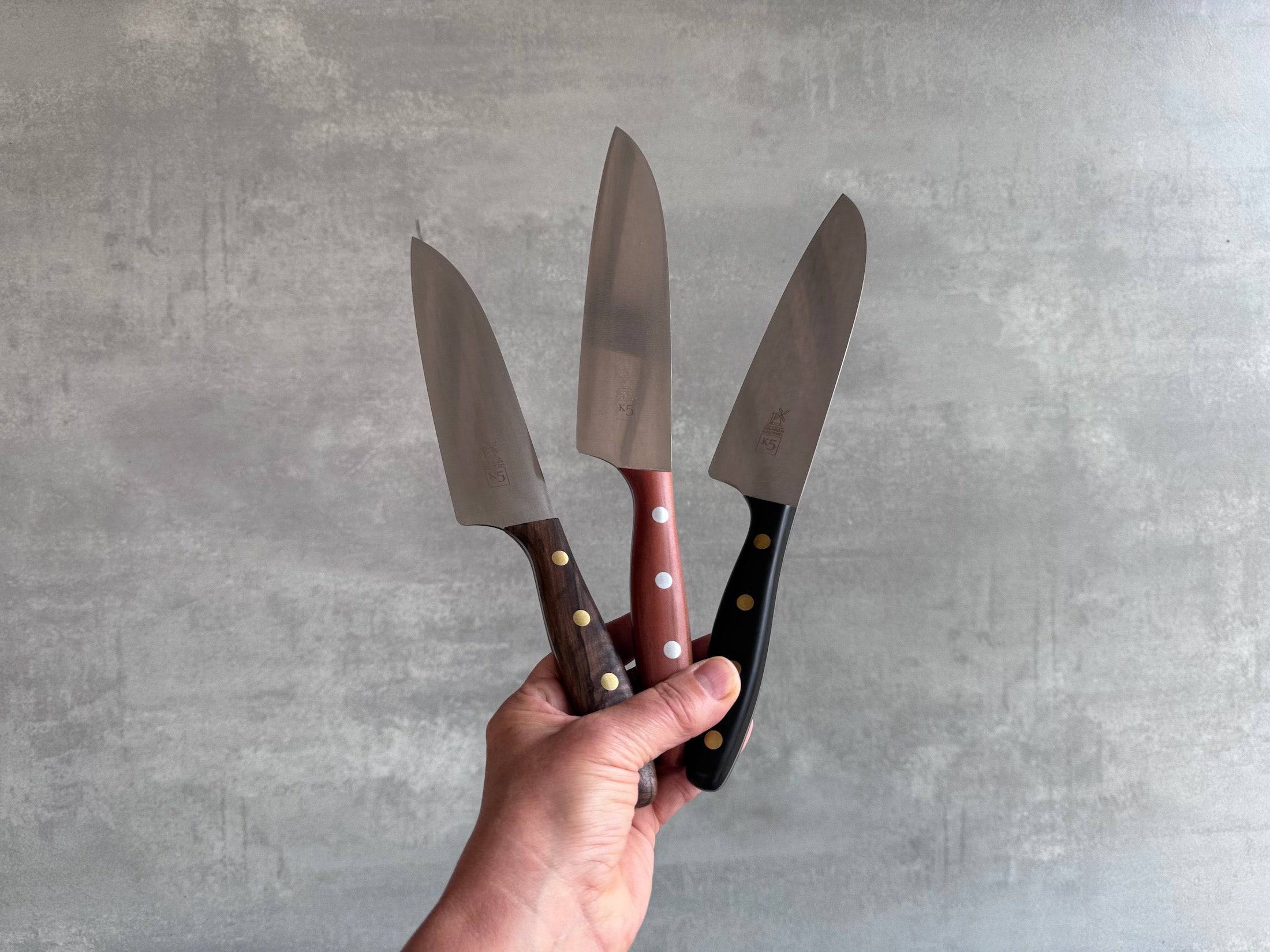 Eine Hand hält 3 K5 Kochmesser in die Höhe.