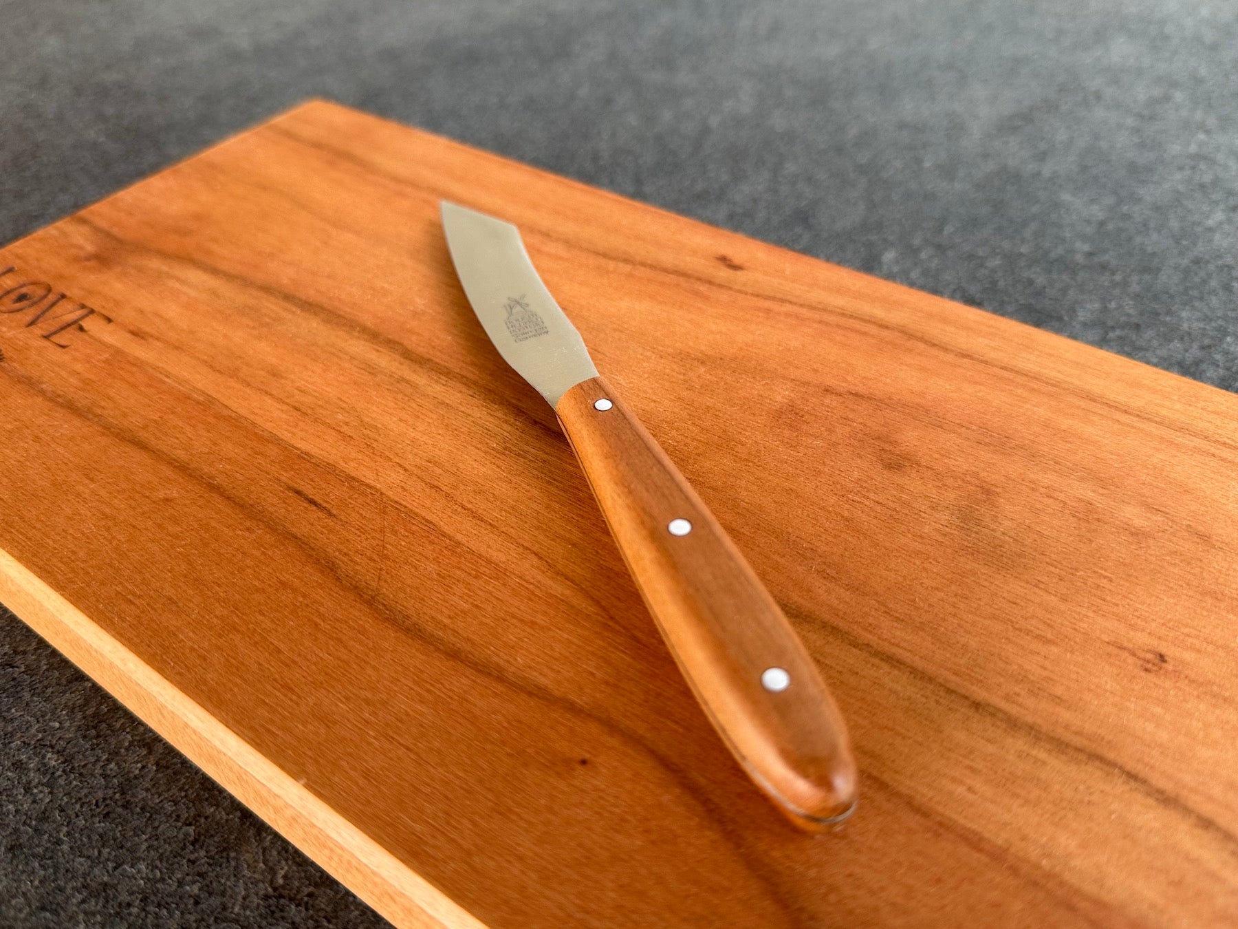 Windmühlenmesser Mini Yatagan mit Kirsche Griff auf einem Kirschbaum Holzbrett.