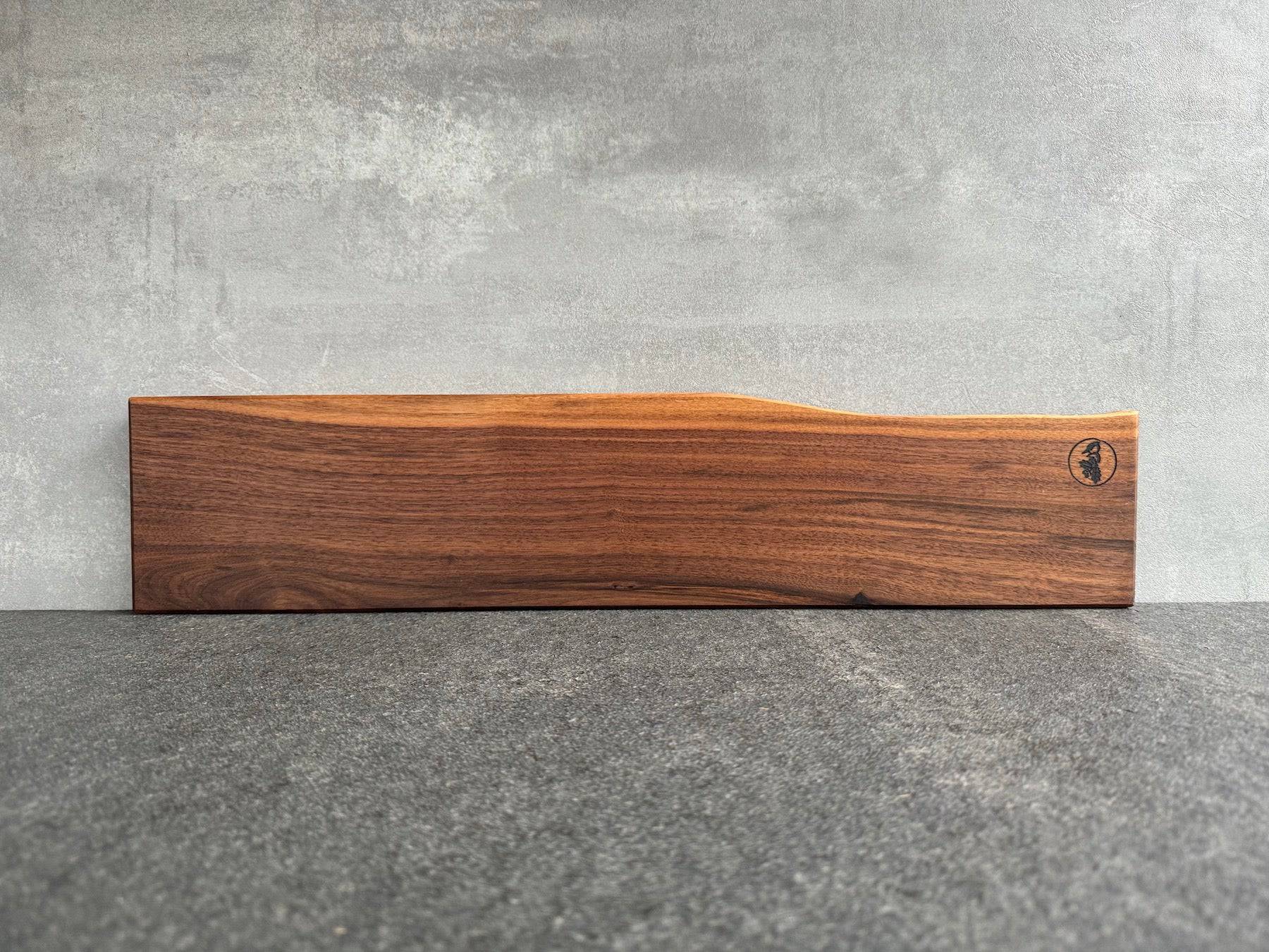 Nussbaum Messerhalter, magnetisch, 60 cm breit, für 9 Messer, an einer Betonwand montiert.
