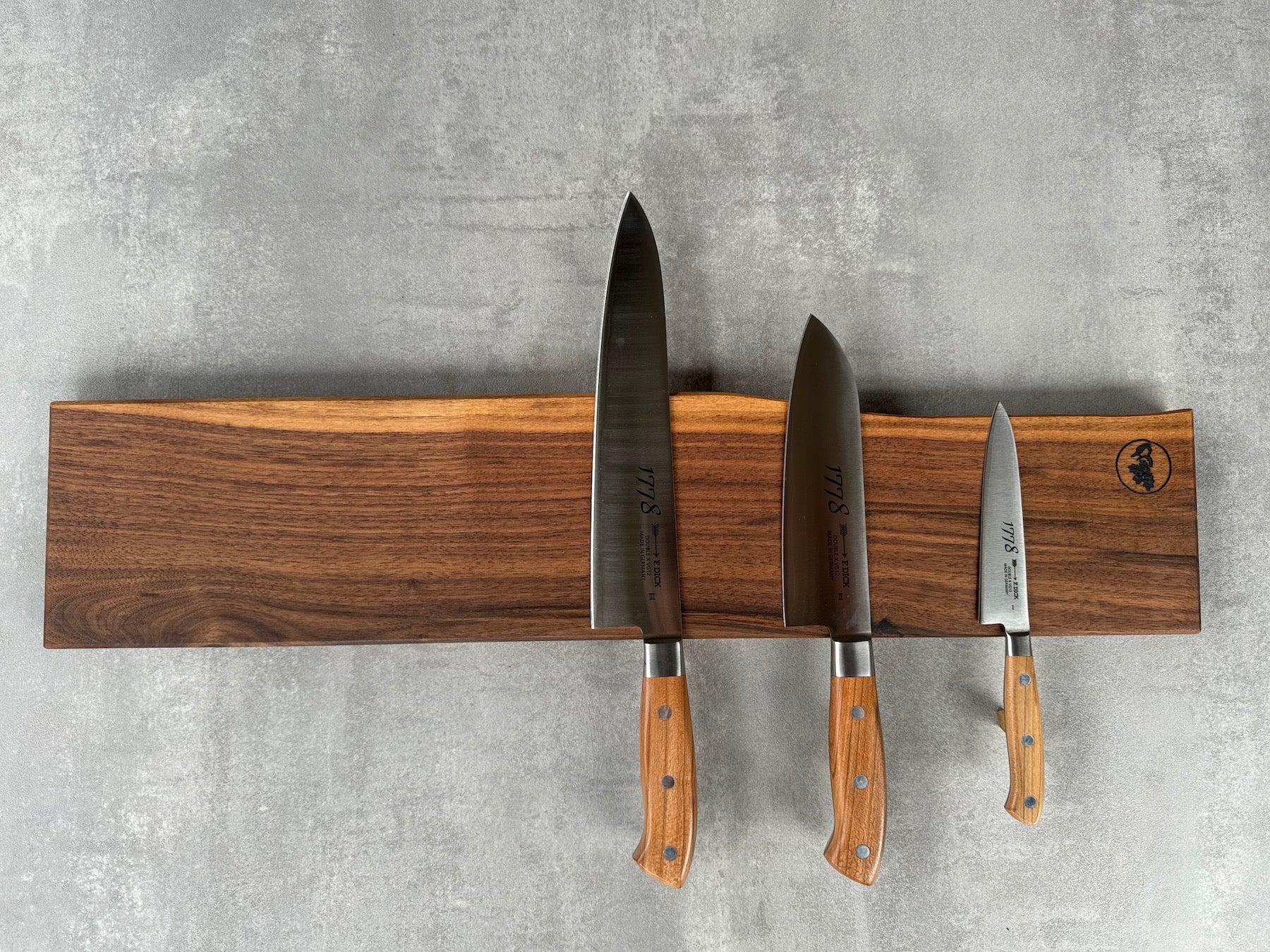 Magnetische Messerleiste für 9 Messer aus massivem Nussbaum mit einer Baumkante. Dekoriert mit 3 Kochmessern von Dick 1778.