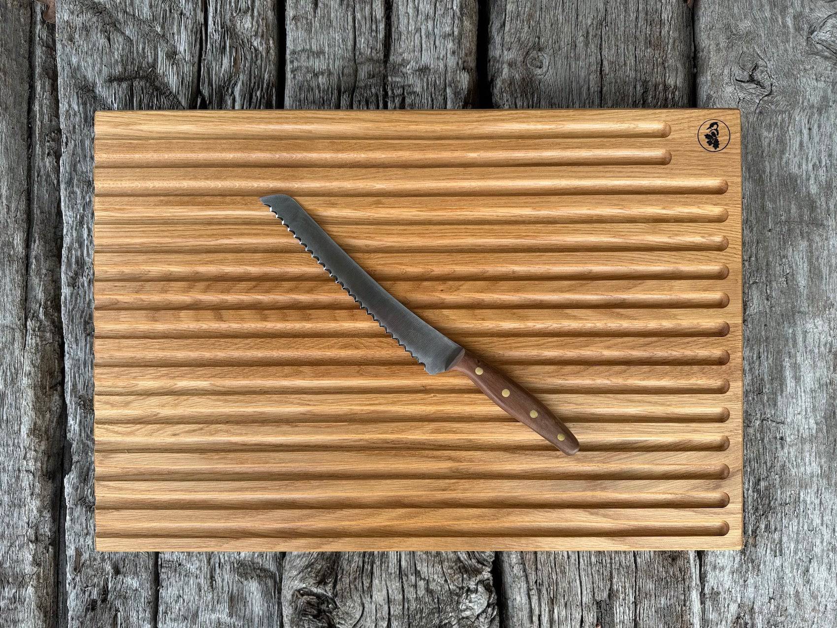 Großes Brotbrett in der Größe 60 x 40 cm aus massiver Eiche auf alten Eichenbalken. Dekoriert mit einem Brotbeidhänder von Windmühlenmesser.