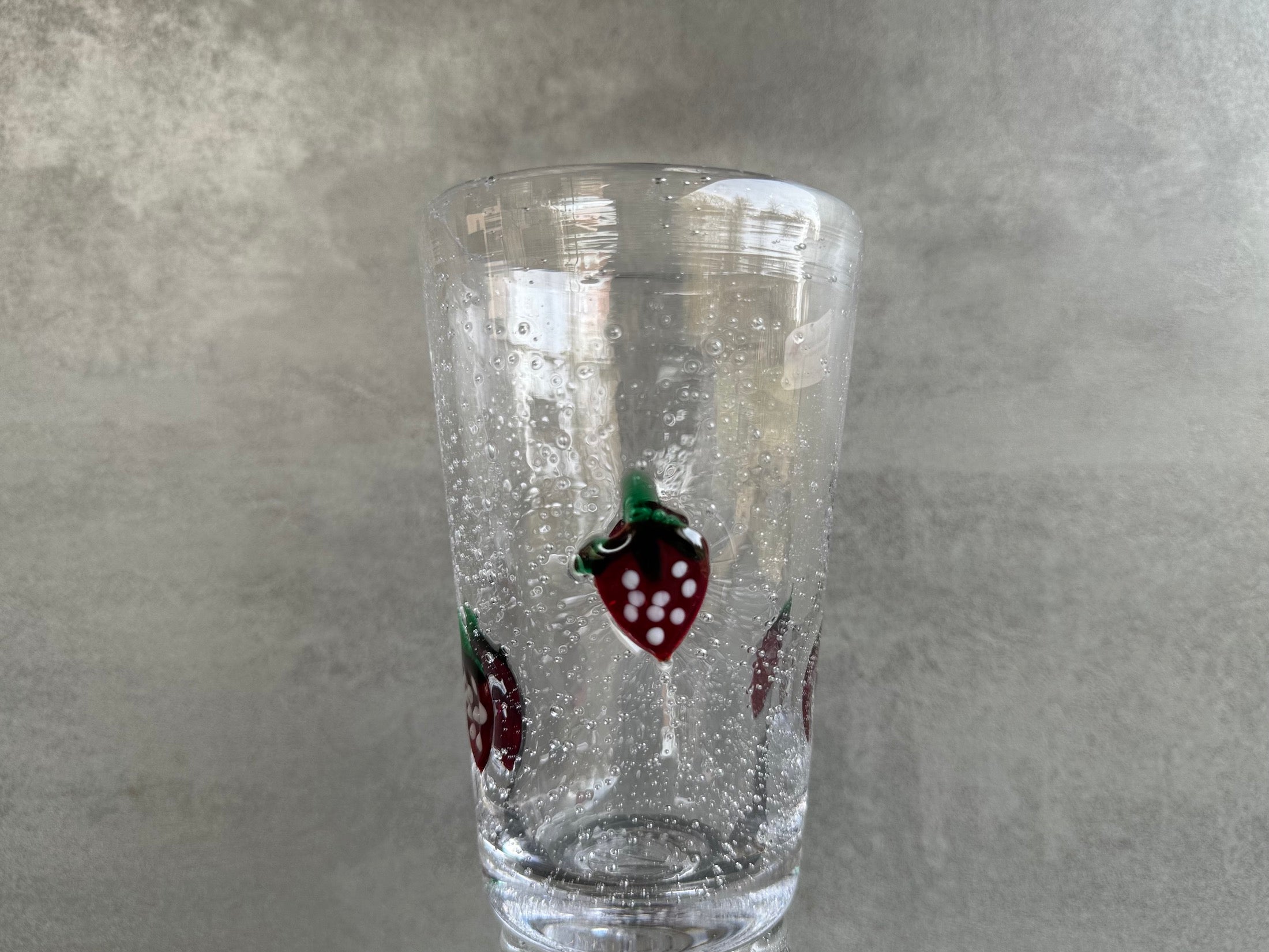 Wasserglas in Becherform mundgeblasen aus antikem Glas mit aufgelegten Erdbeeren.
