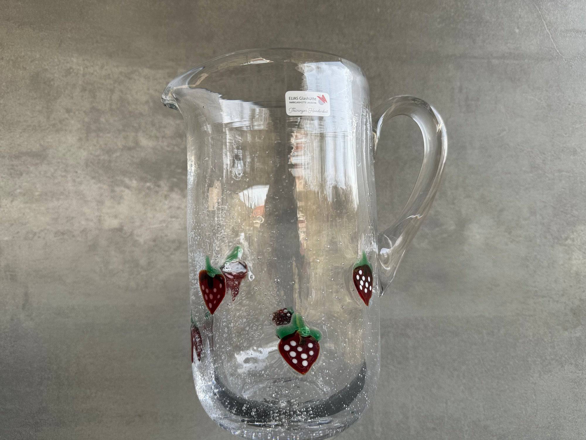 La Fresa Wasserkrug aus Antikglas mit aufgelegten Erdbeeren.