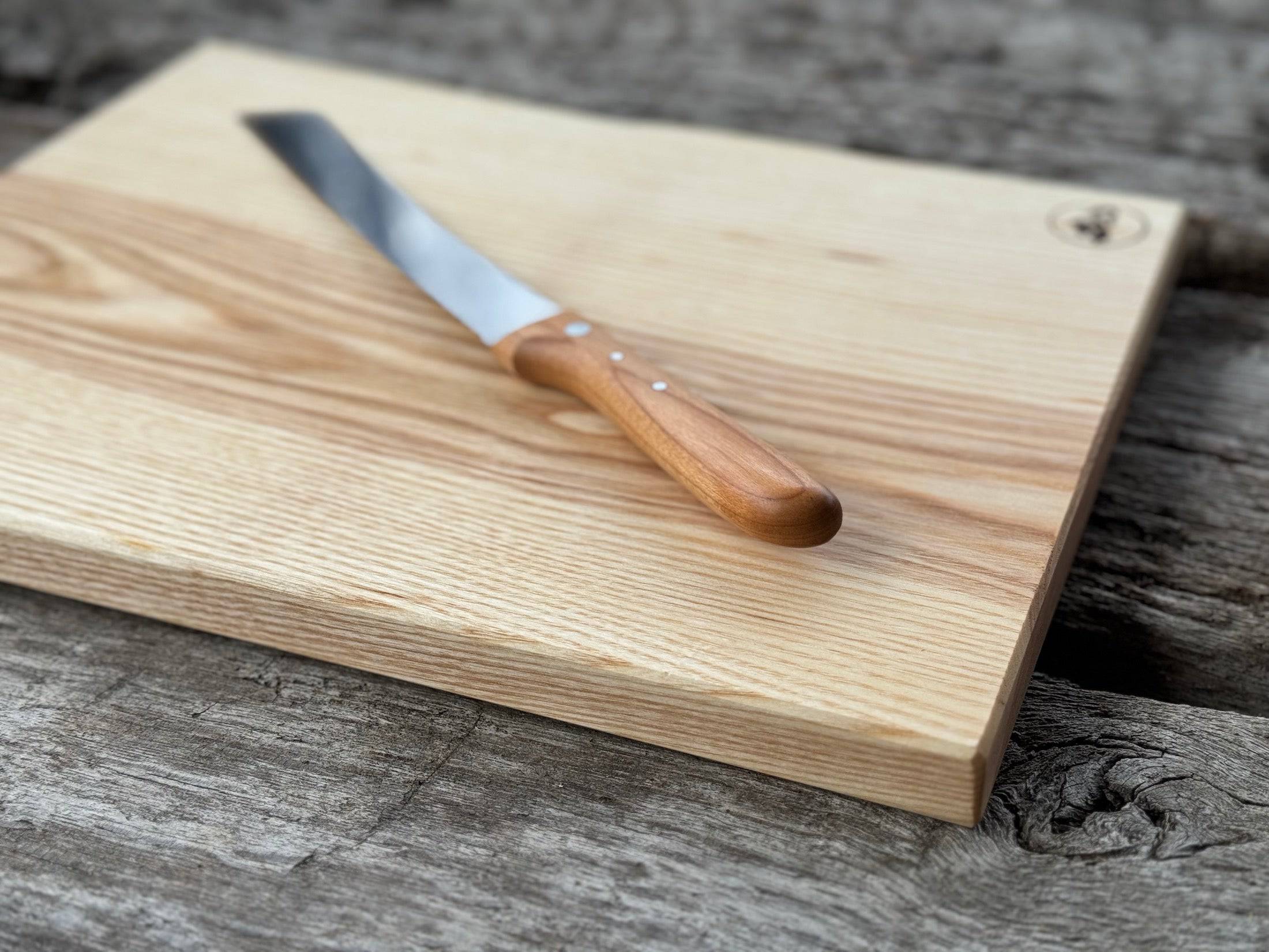 Brotbrett aus einem Stück Vogelbeere mit Jahresringen und einem Brotmesser.