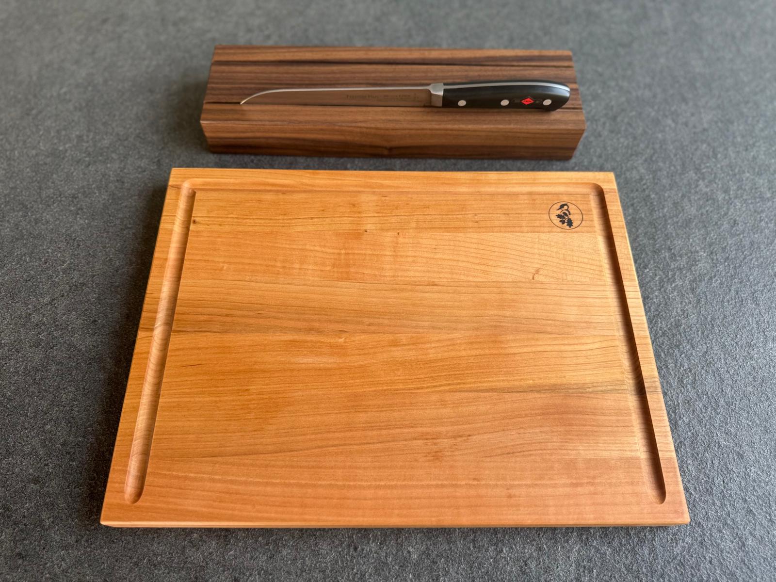 Kirschbaum Schneidebrett mit U-Saftrille und Griffmulden. Mit einem flexiblen Messerhalter aus Nussbaum.