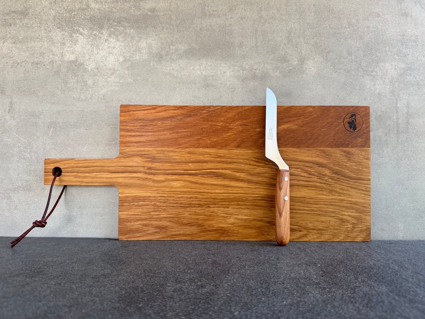 Eiche Schneidebrett mit Griff und Lederband und einem Käsemesser von Windmühlenmesser.