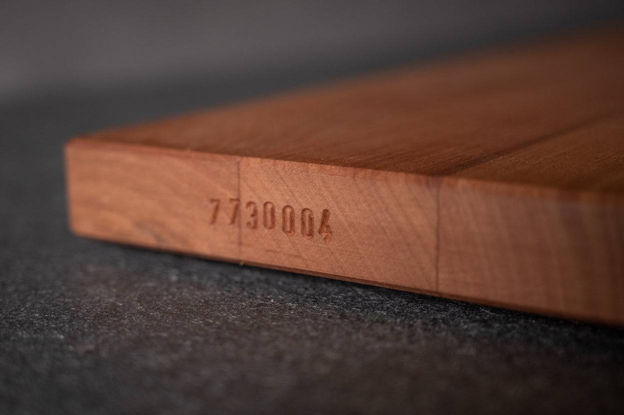 Eingeschlagene Seriennummer seitlich in einer Kochfeldabdeckung von Spessartbrett.