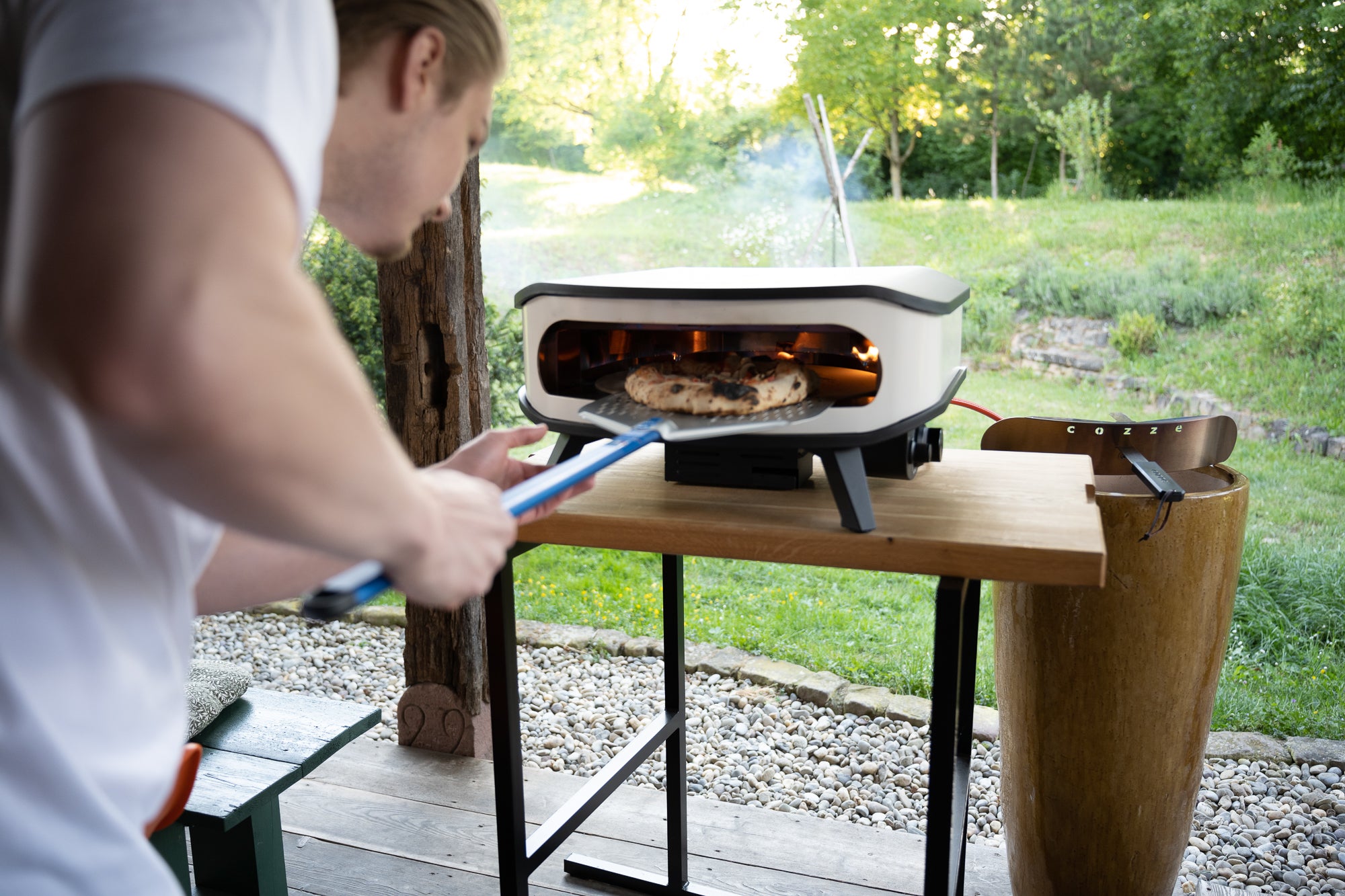 Pizzabäcker holt gerade eine Pizza aus einem Pizza Cozze Ofen mit einer Schaufel von Gi.Metall