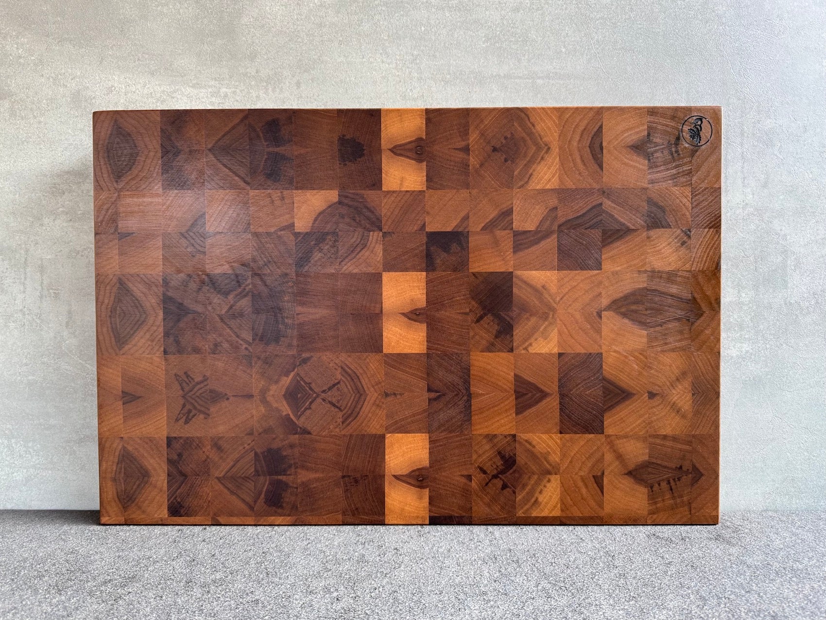 Großer Hirnholz Schneideblock aus Nussbaum massiv an einer Betonwand.