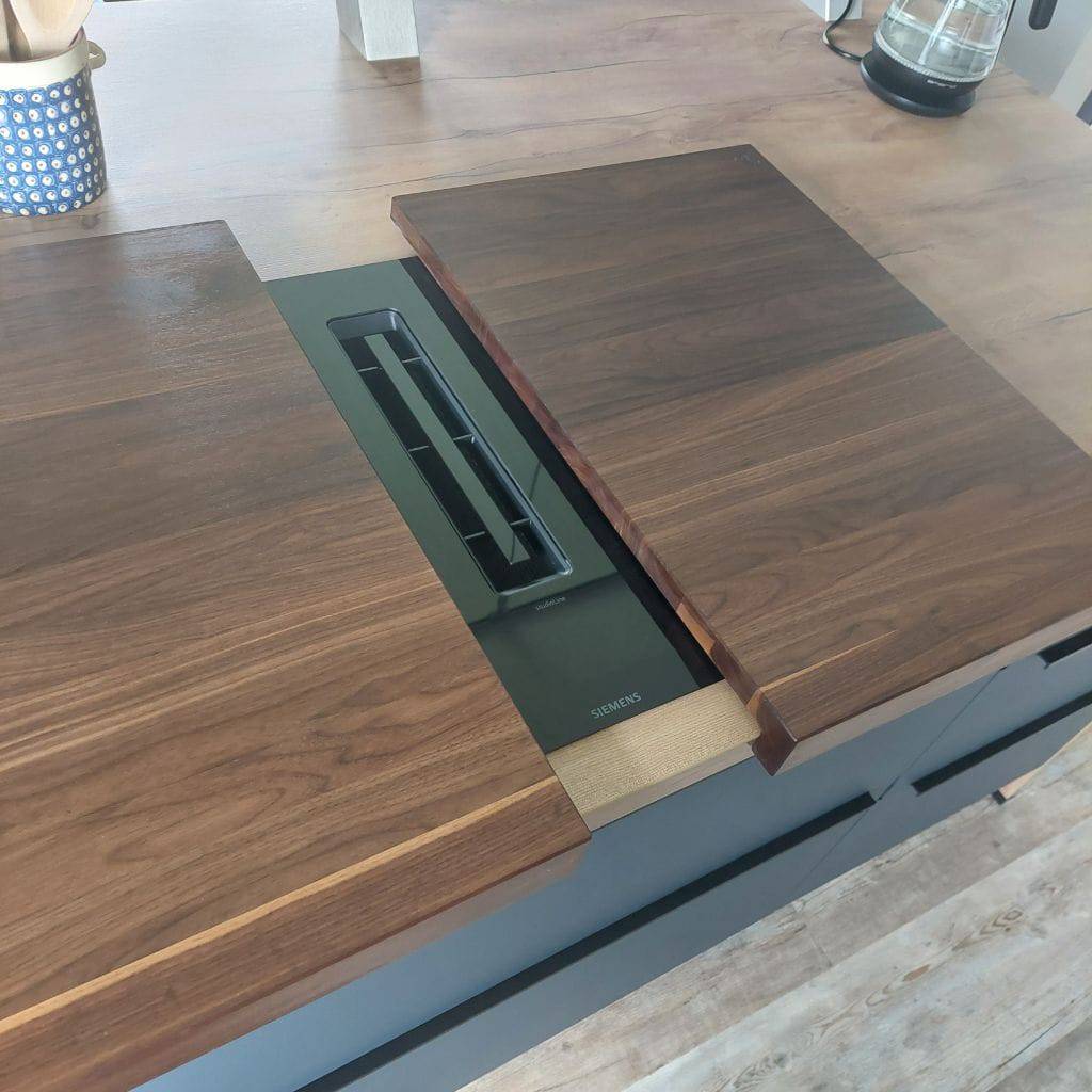 Leicht geöffnete Kochfeldabdeckung bei einem Siemens Kochfeld mit integriertem Dunstabzug.