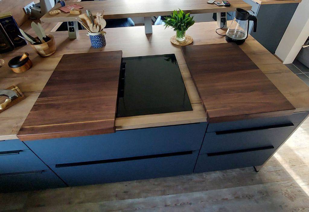 Geöffnete Kochfeldabdeckung aus massivem Nussbaum mit einem Anschlag. 2-teilig. Präsentiert in einer privaten Küche.