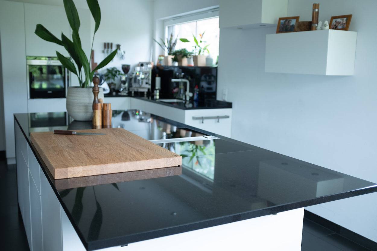 80 cm langer Schneideblock aus massiver Eiche in einer weißen Küche auf einer schwarzen Arbeitsplatte.