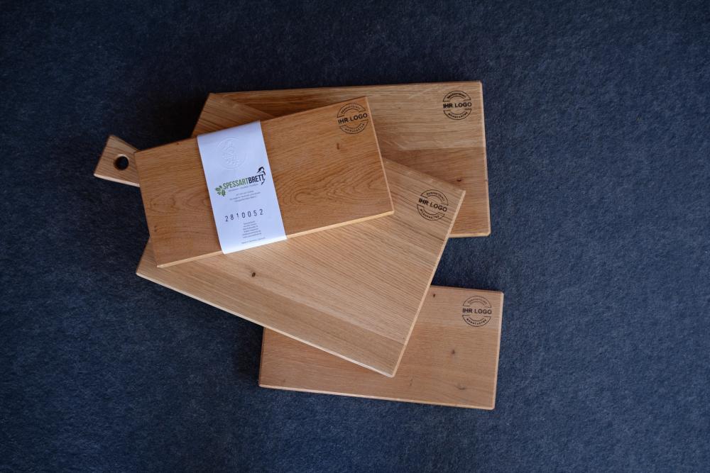 4 Eiche Schneidebretter auf einer Steinplatte, Werbung von Spessartbrett für nachhaltige Geschenke für Kunden und Mitarbeiter.