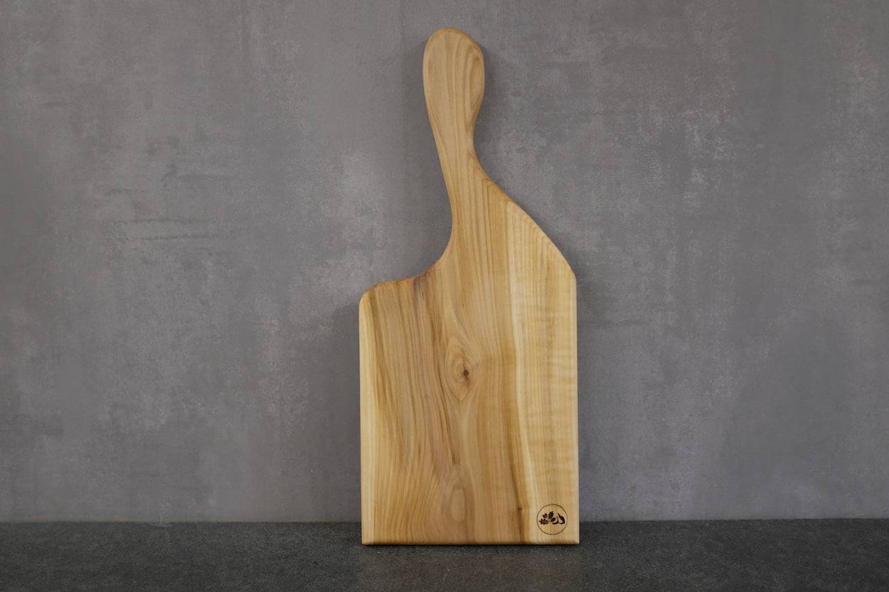 Vogelbeere Vollholz Brett mit Griff angehen an einer Betonwand. Vorderseite mit einem Spessartbrett Stempel. Unikat.