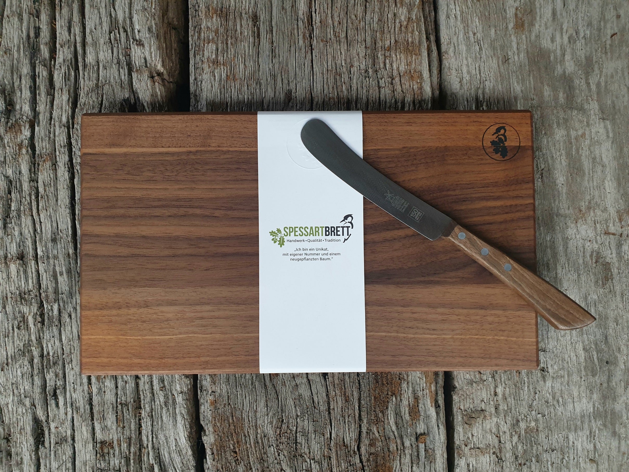 Feines Nussbaum Vesperbrett mit Spessartbrett Banderole, auf dem ein Buckels von Windmühlenmesser liegt. Auf alten Eichenbalken .