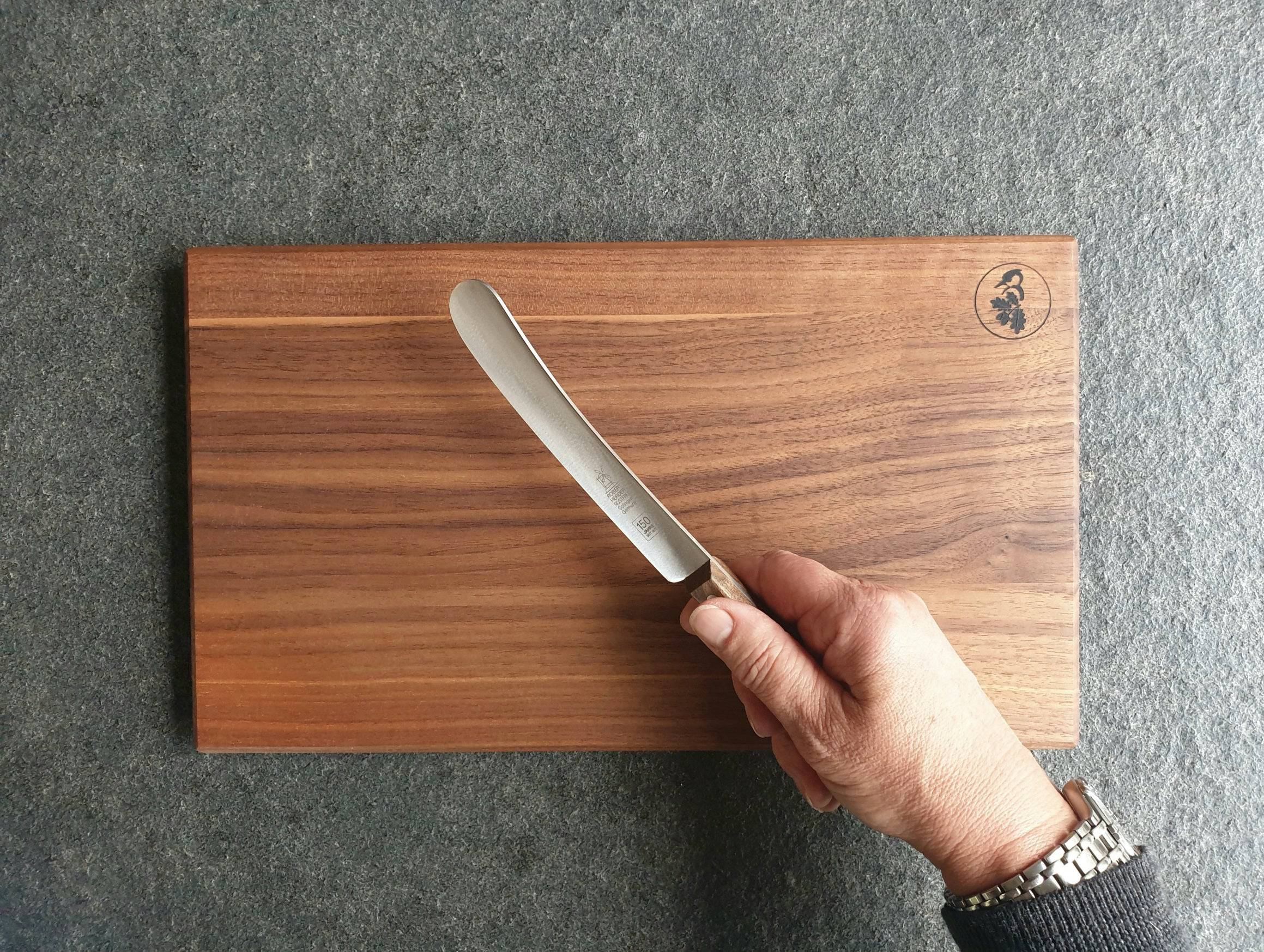 In der Hand ein Buckels 150 Jahre Jubiläum mit Nussbaum Griff. Im Hintergrund ein Nussbaum Vesperbrett.