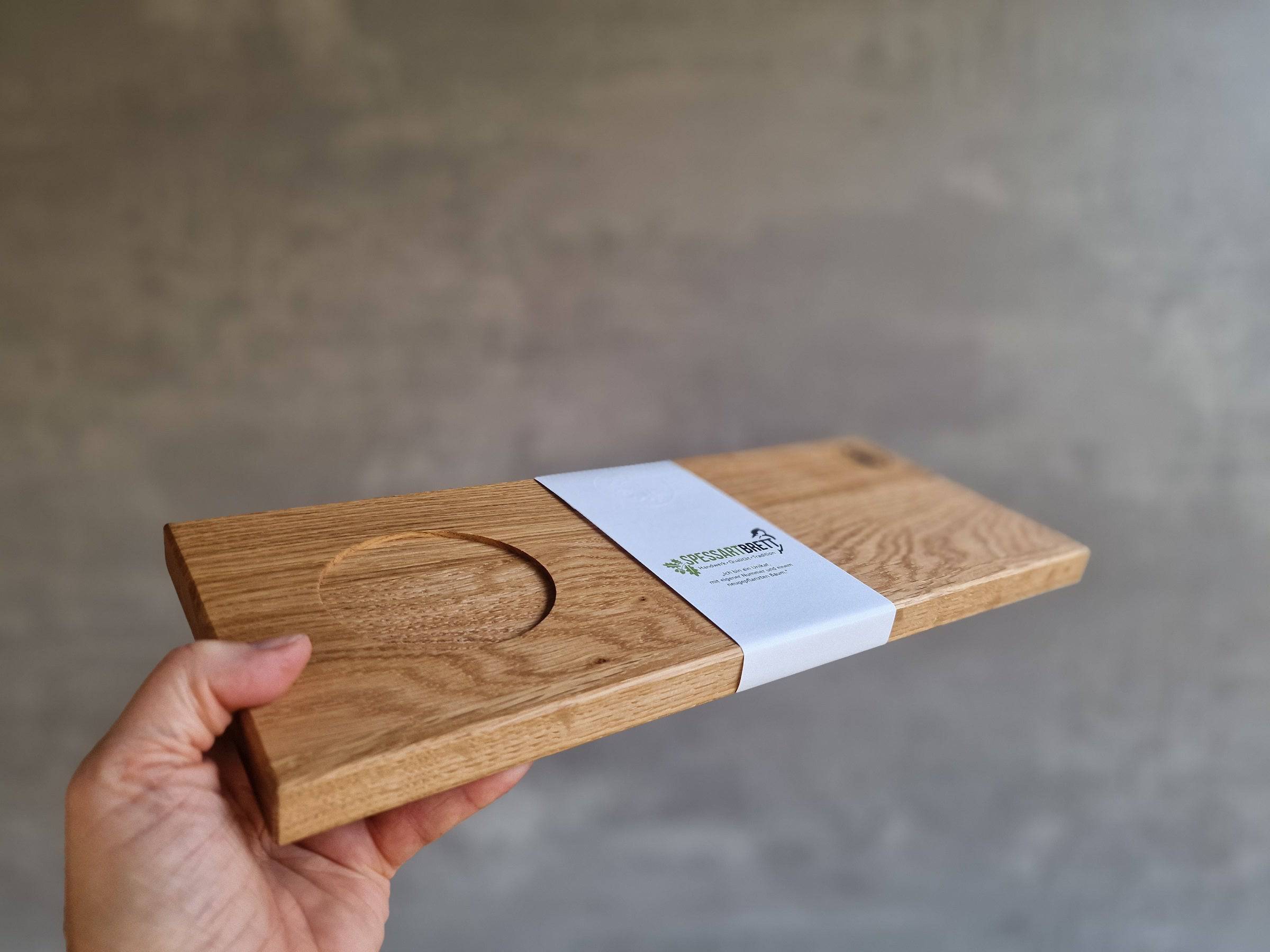 Eine Hand hält ein Eiche Holz Tablett für eine große Tasse Cappuccino.