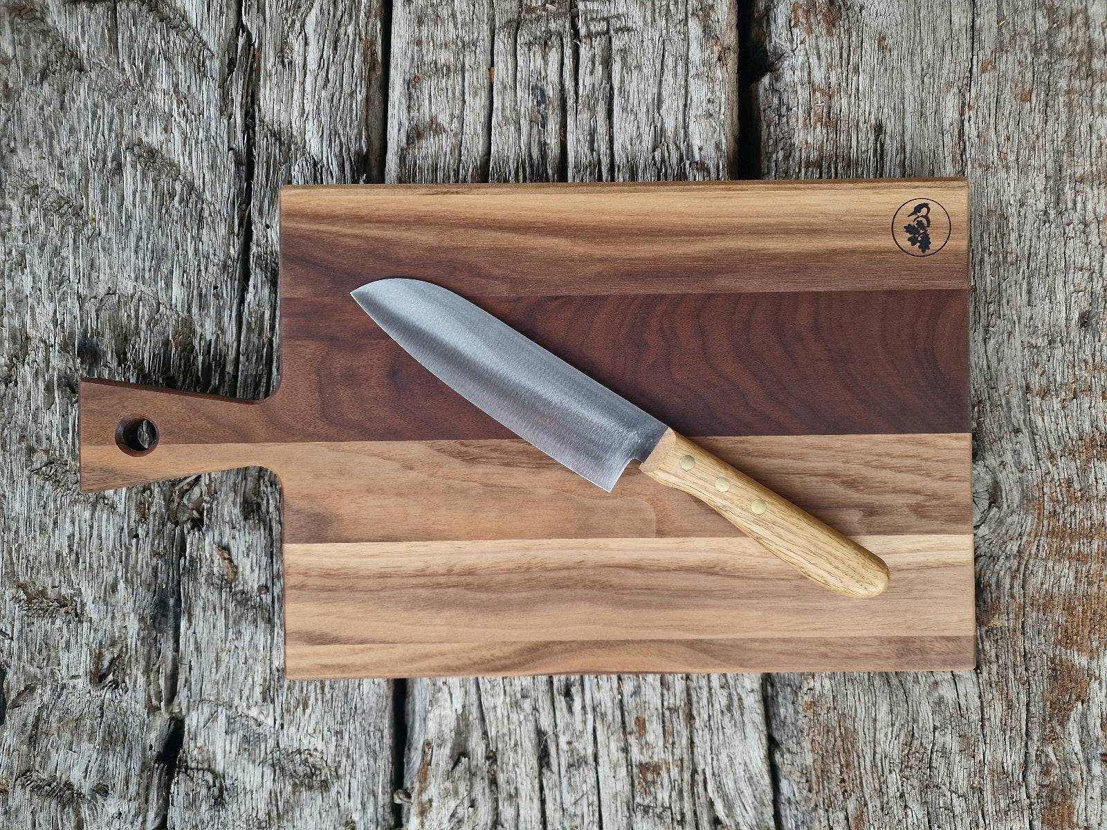 Gemasertes Nussbaum Stielbrett mit einem Windmühlenmesser Kochmesser mit Eiche-Griff, auf alten Eichenbalken.