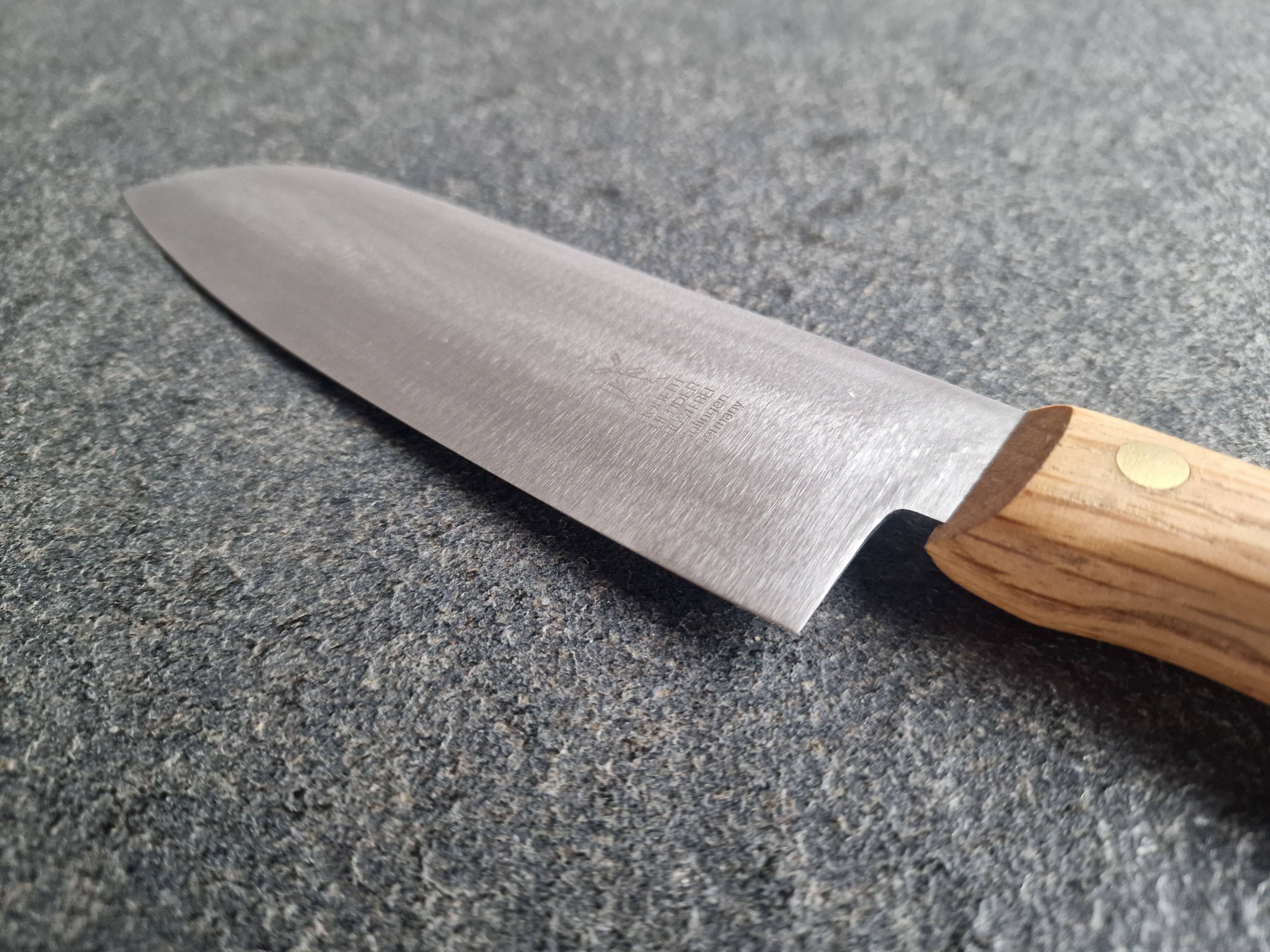 Detailansicht der Klinge eines Santoku Messers auf einer Steinplatte.