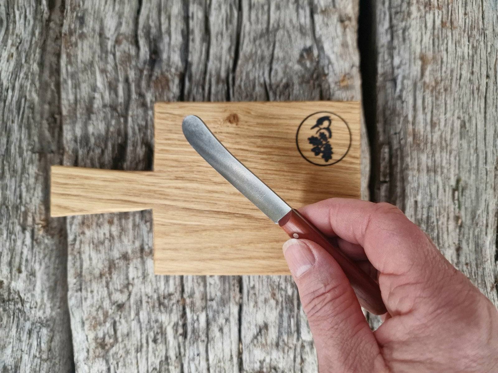 In der Hand ein kleines Butter Buckels Messer. Auf alten Eichenbalken ein Mini Eichenbrett mit Stiel.