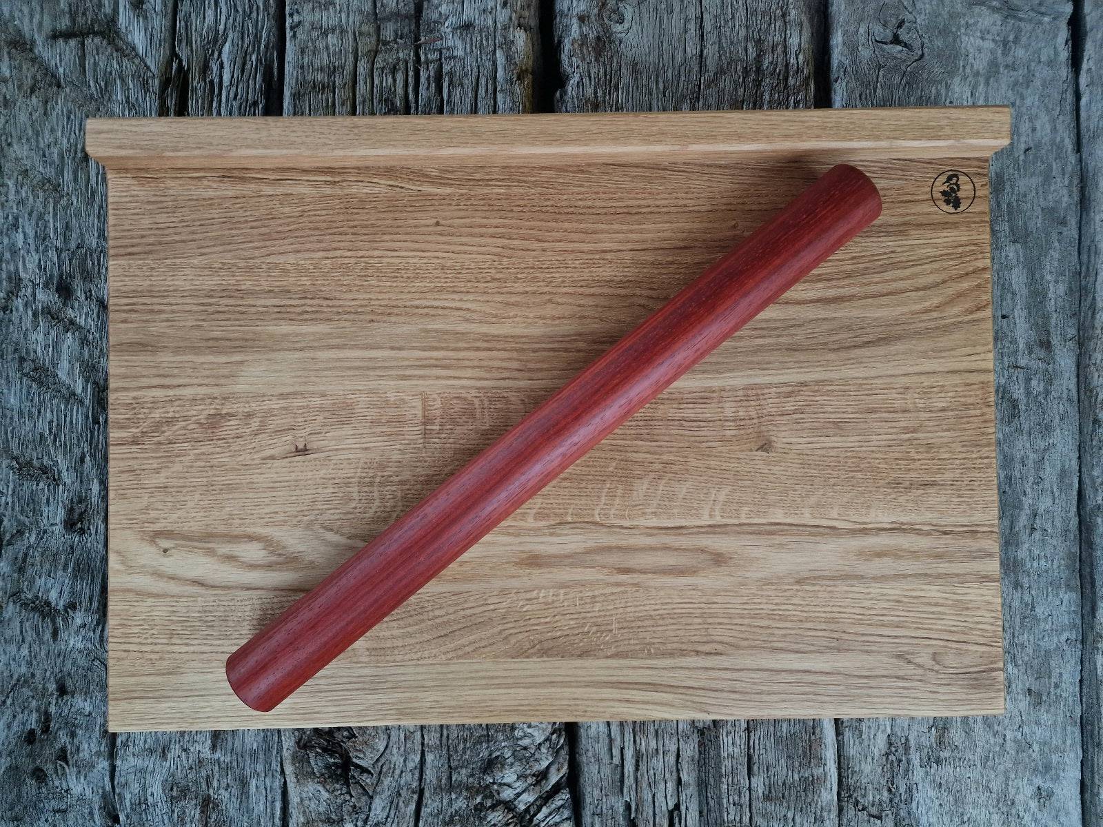 Leuchtend rotes Korallenrot: Padouk Teigrolle auf einem Backbrett aus Eiche, auf alten Eichenbalken.