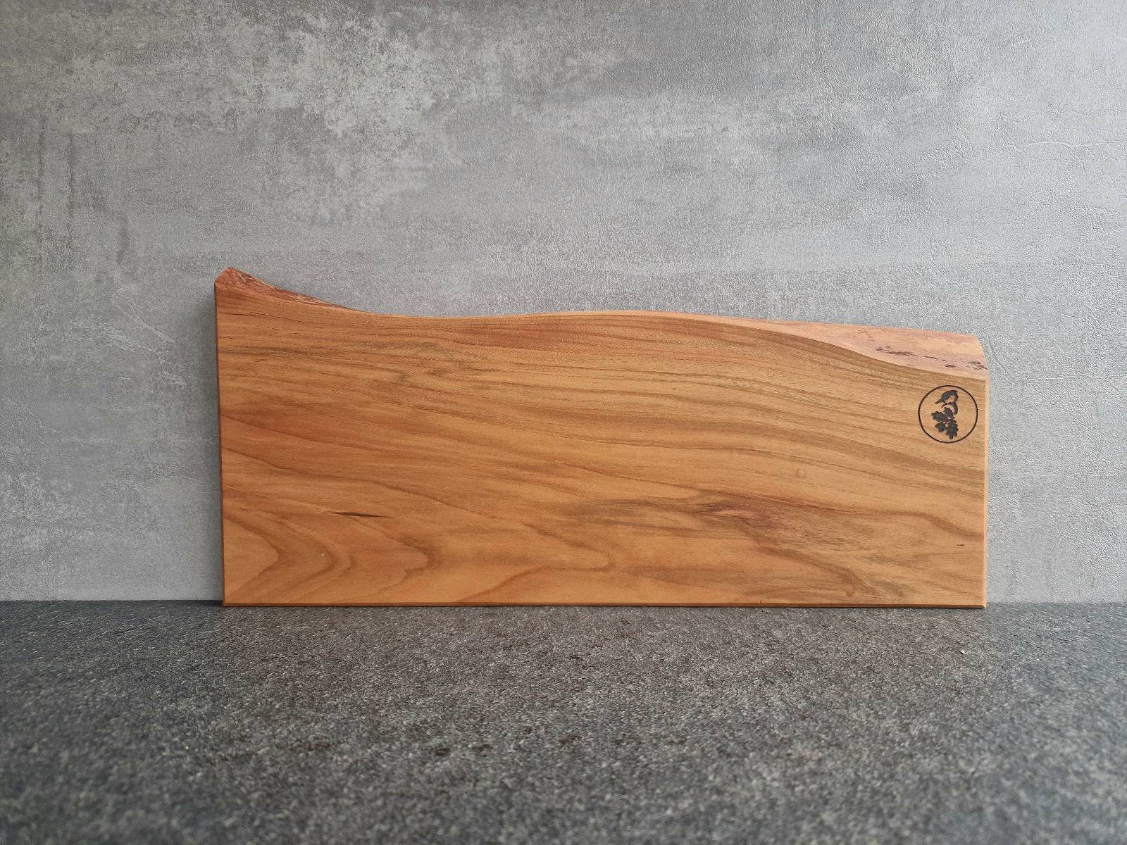 Magnetischer Messerhalter aus Kirschbaum mit Baumkante an einer Betonwand.