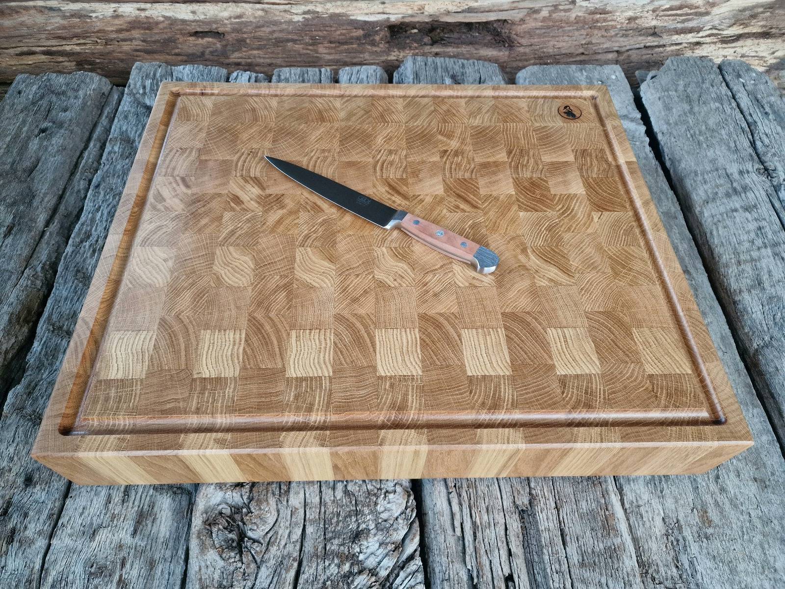 Güde Kochmesser mit langer schmaler Klinge auf einem Stirnholz Schneideblock mit Saftrille auf historischen Eichenbalken.