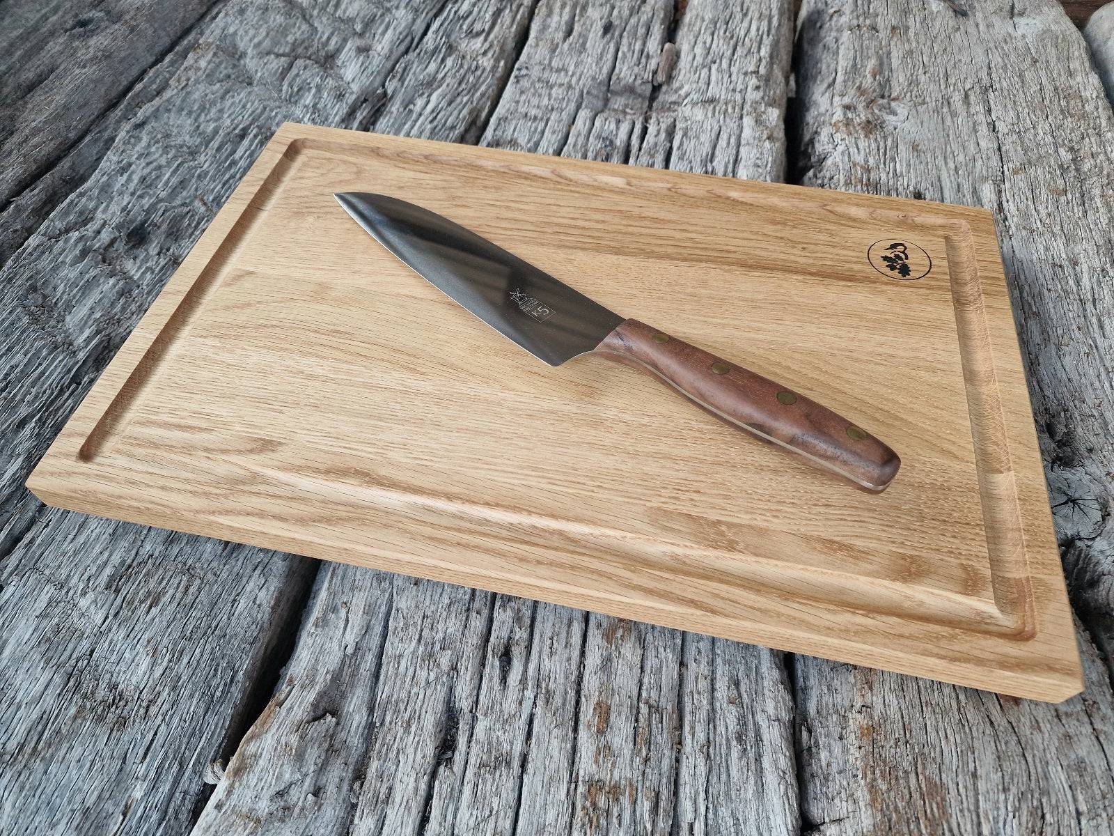 Kochmesser K5 mit Walnuss-Griff auf einem Saftrillenbrett aus Eiche, auf alten Eichenbalken.